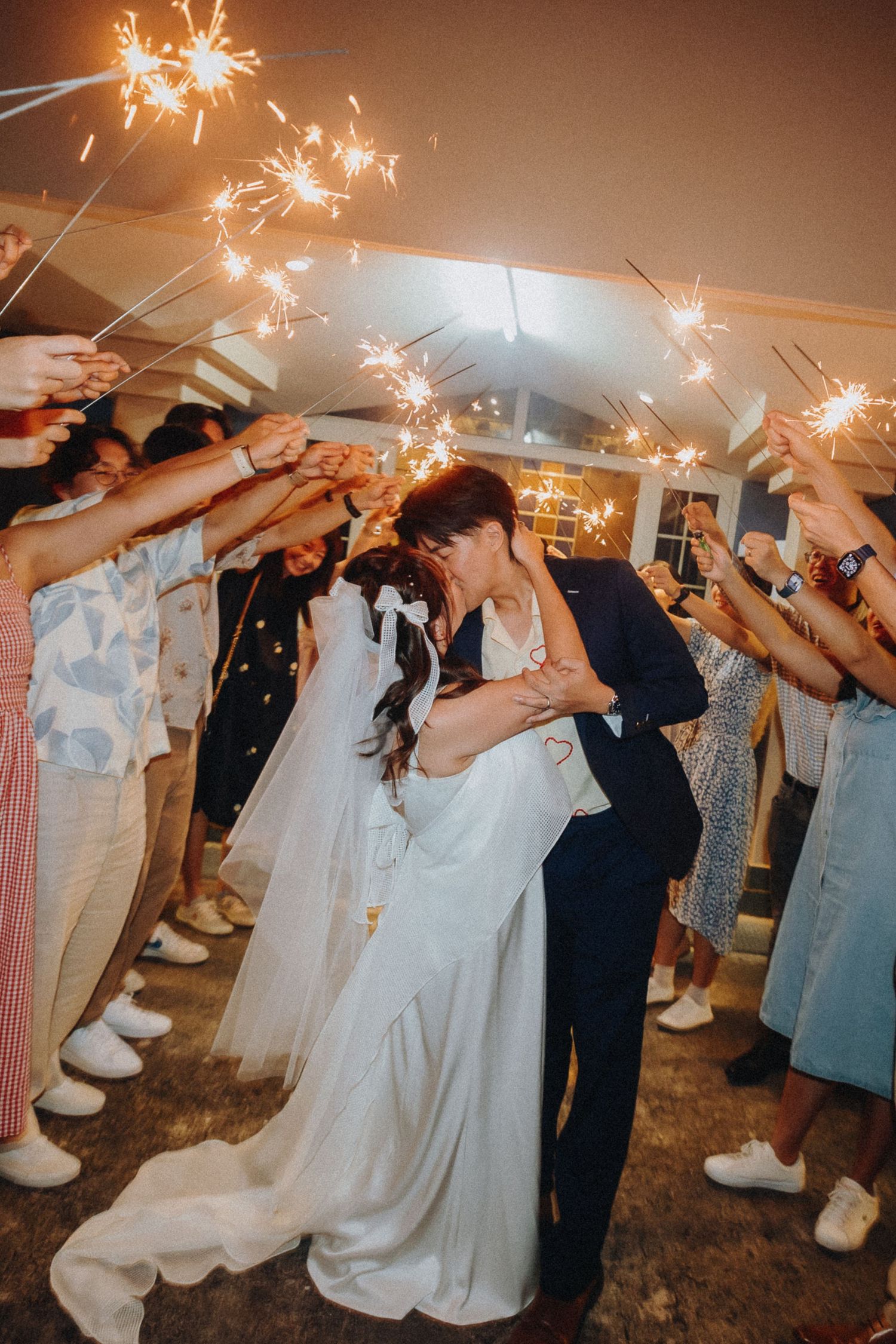 Newlyweds share romantic moment under sparklers held by wedding guests.