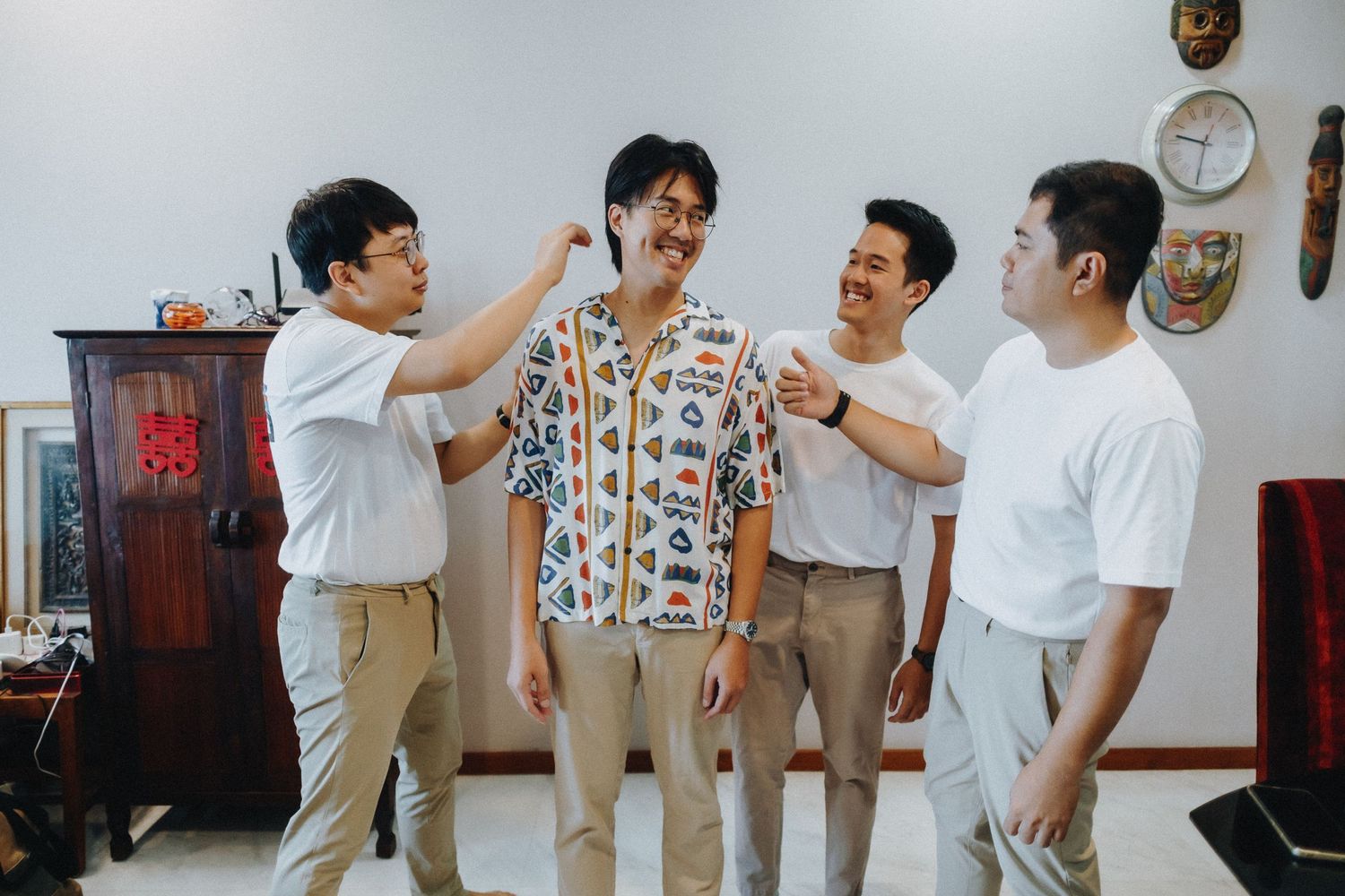 A group of friends in casual attire stand together laughing and having a fun conversation indoors.