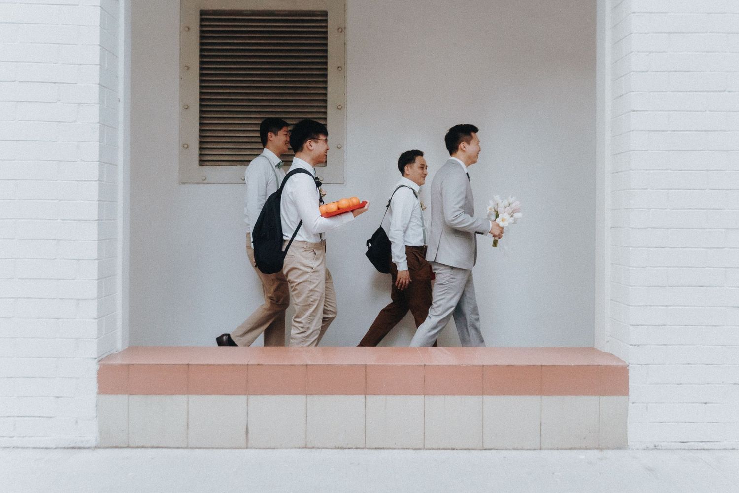 Group of people walking in synchronized formation along a covered walkway of a building.