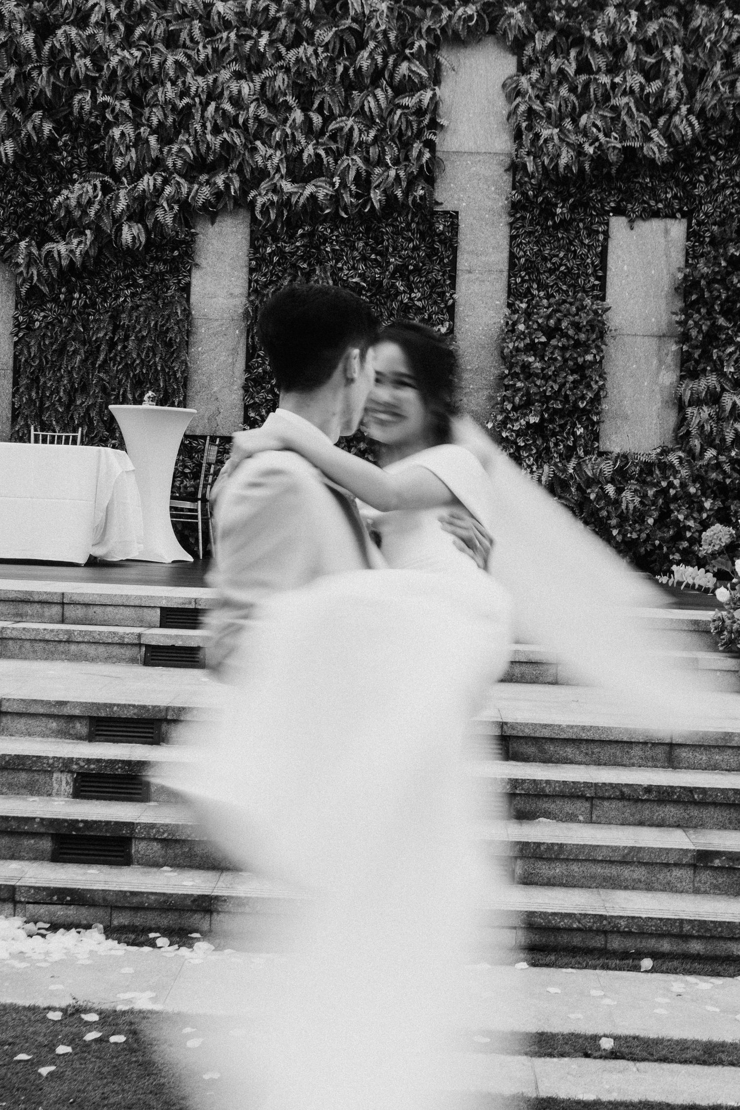 Motion blur captures a dramatic black and white sequence of a bride running past stone columns.