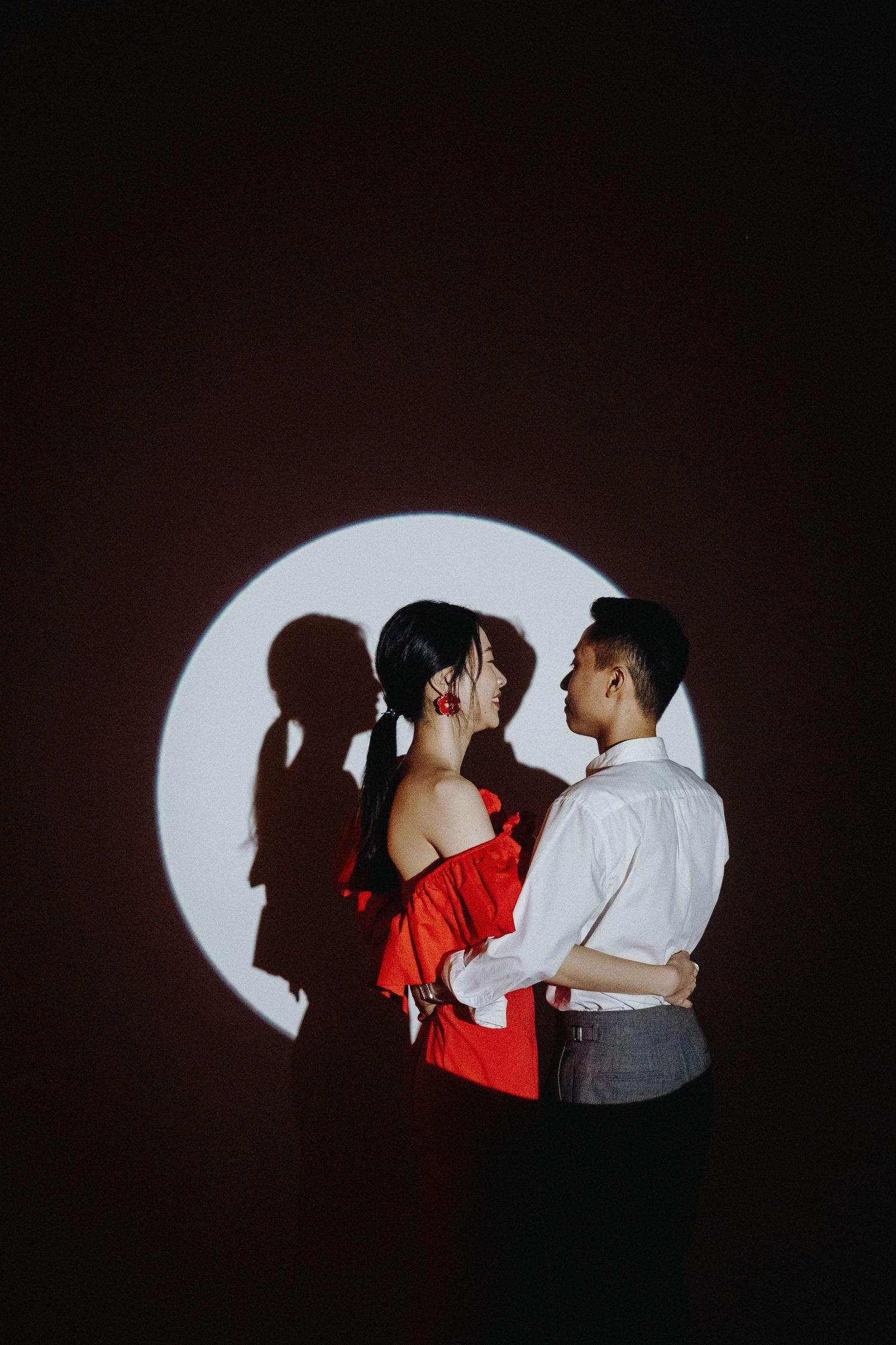 Artistic silhouette portrait of couple in spotlight against dark background showing dramatic contrast.