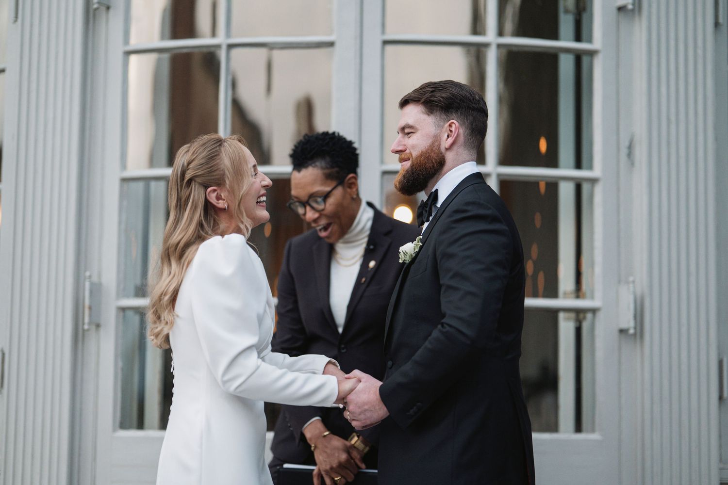 A husband and wife having their first kiss as the officiant gets out of their way