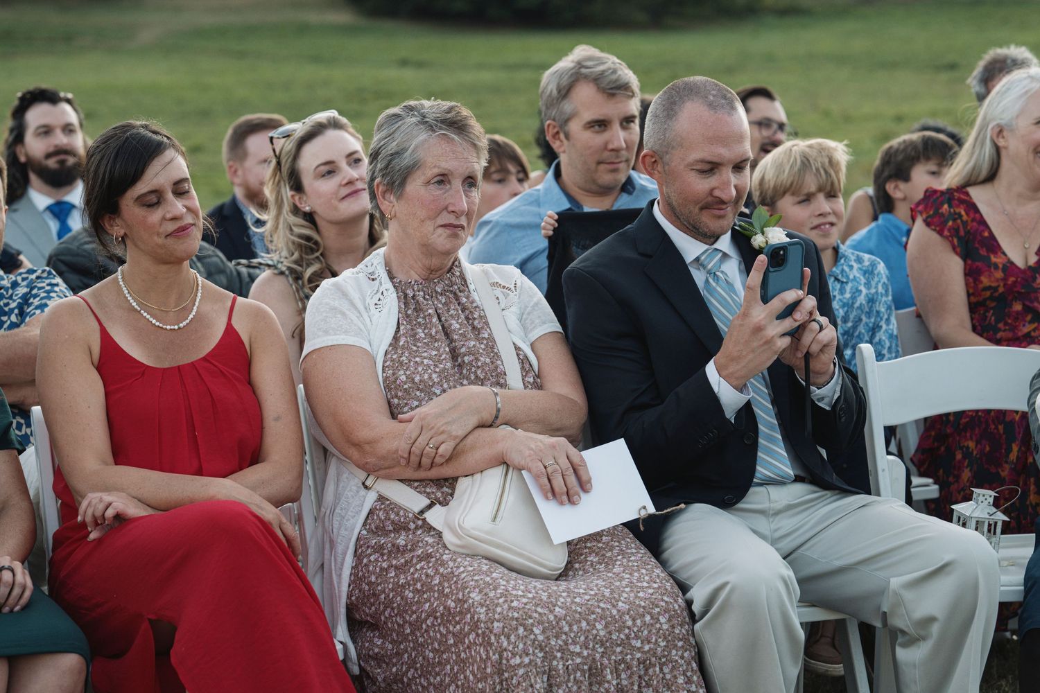 A family member taking pictures of a wedding with their phone