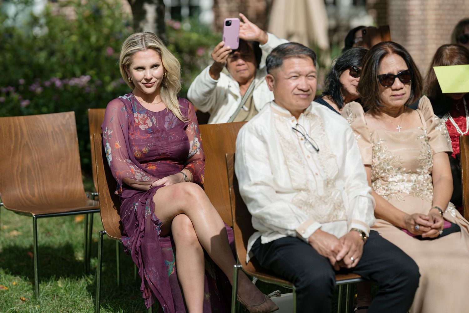 A family member taking pictures of a wedding with their phone