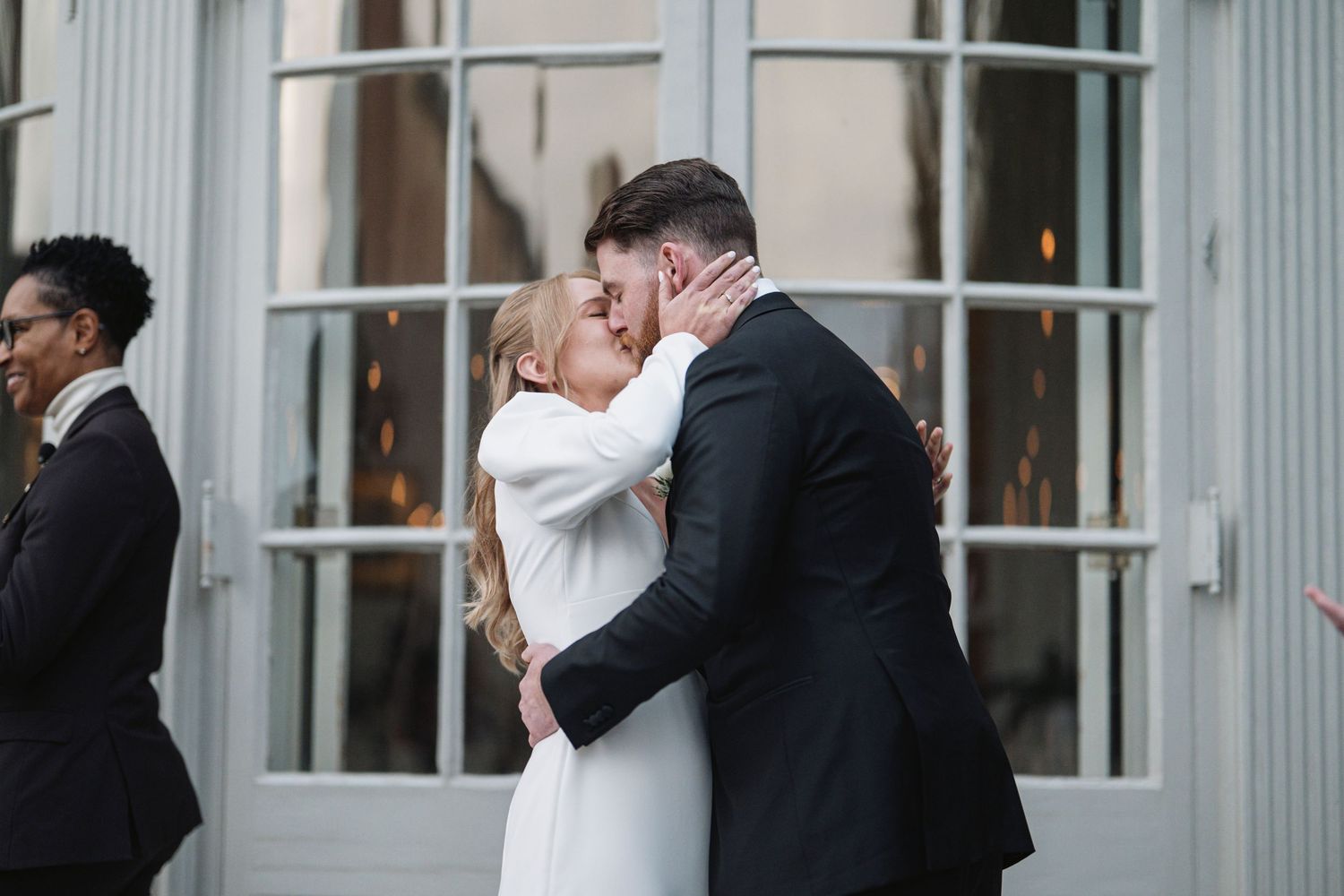 A husband and wife having their first kiss as the officiant gets out of their way
