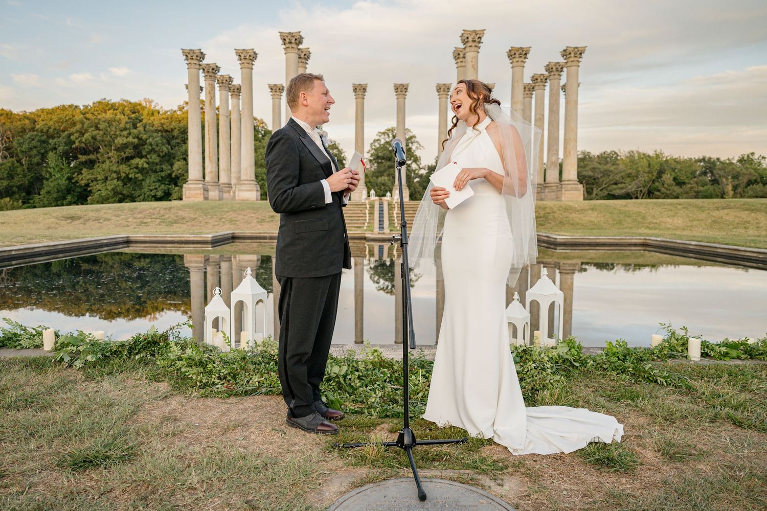 A bride and groom on their wedding day. There is a microphone stand between them