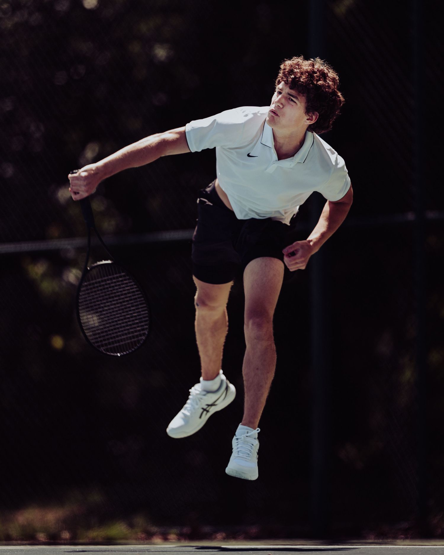 Tennis player in white shirt serves dynamically on court – athletic action photo byDaviel.com in Tulsa