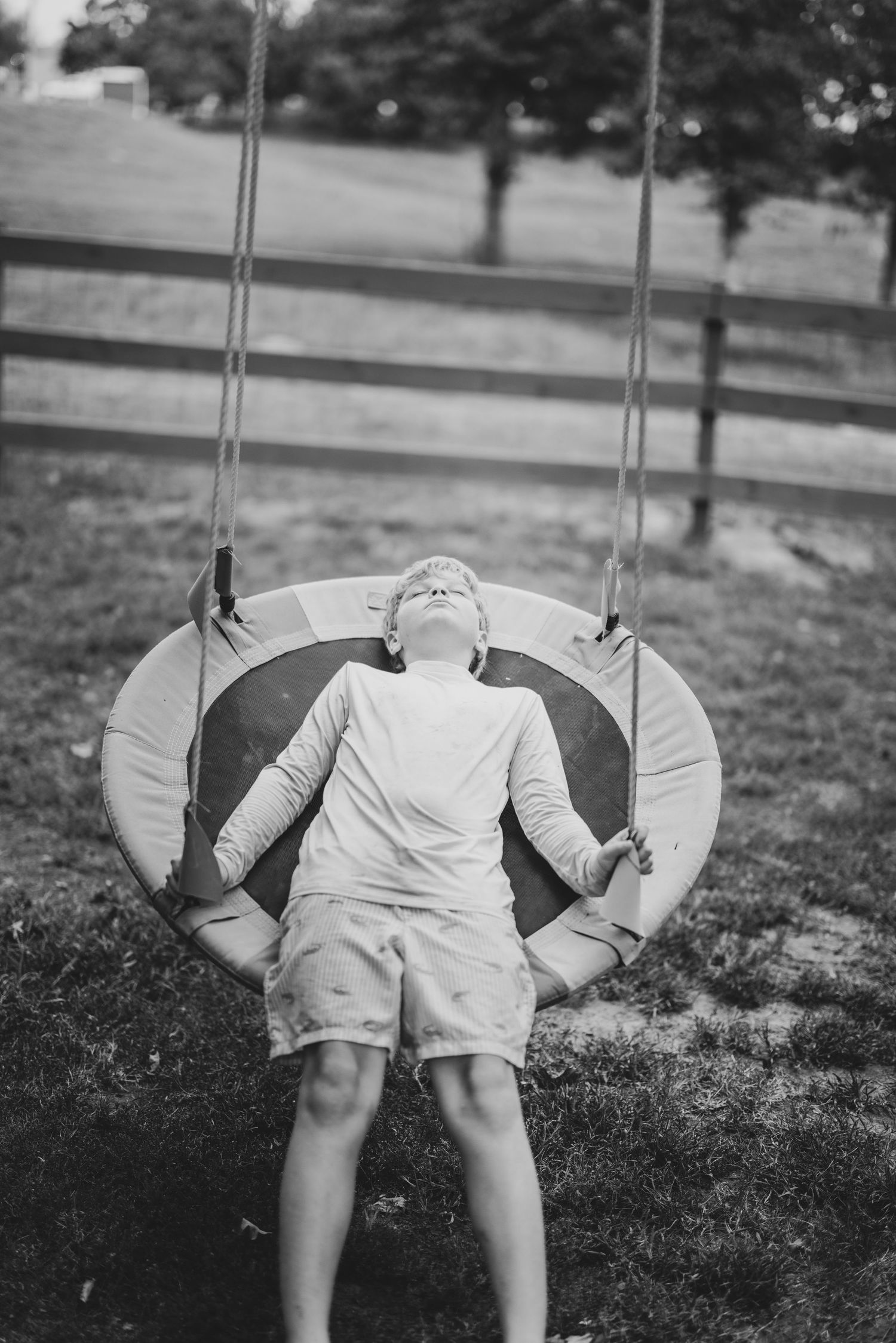 A black and white photo sequence shows someone swinging back and forth on a playground swing. – Tulsa family photo byDaviel.com