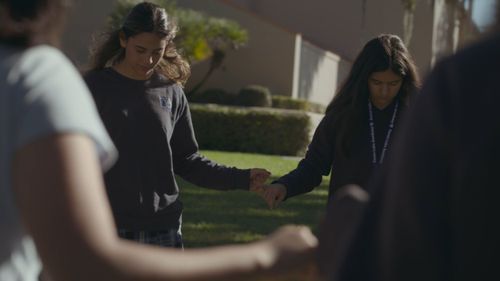 Forest Lake Academy students holding hands in a prayer circle on campus, a frame from the film