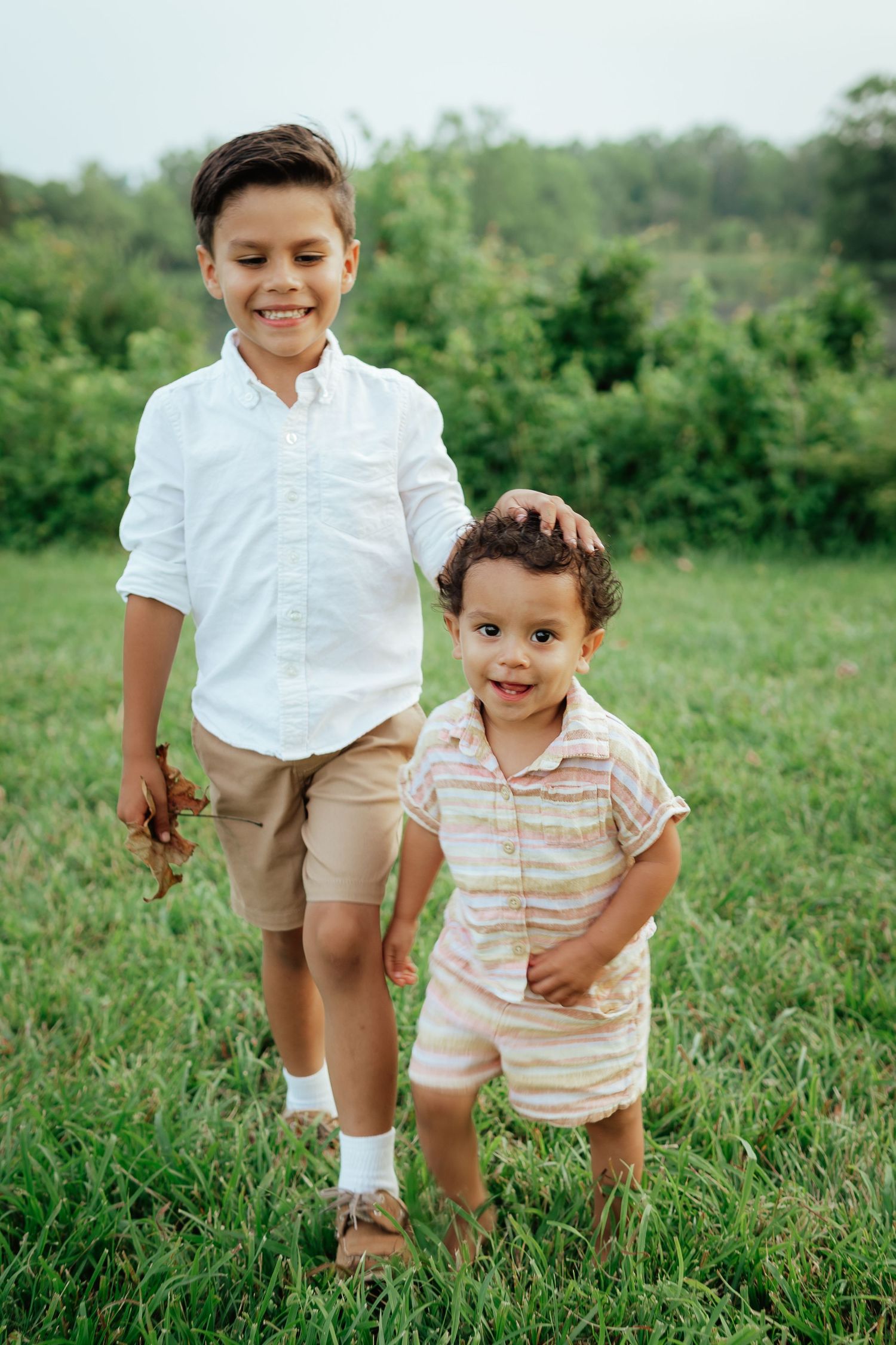 Young children in coordinated outfits run and play in a lush green field.