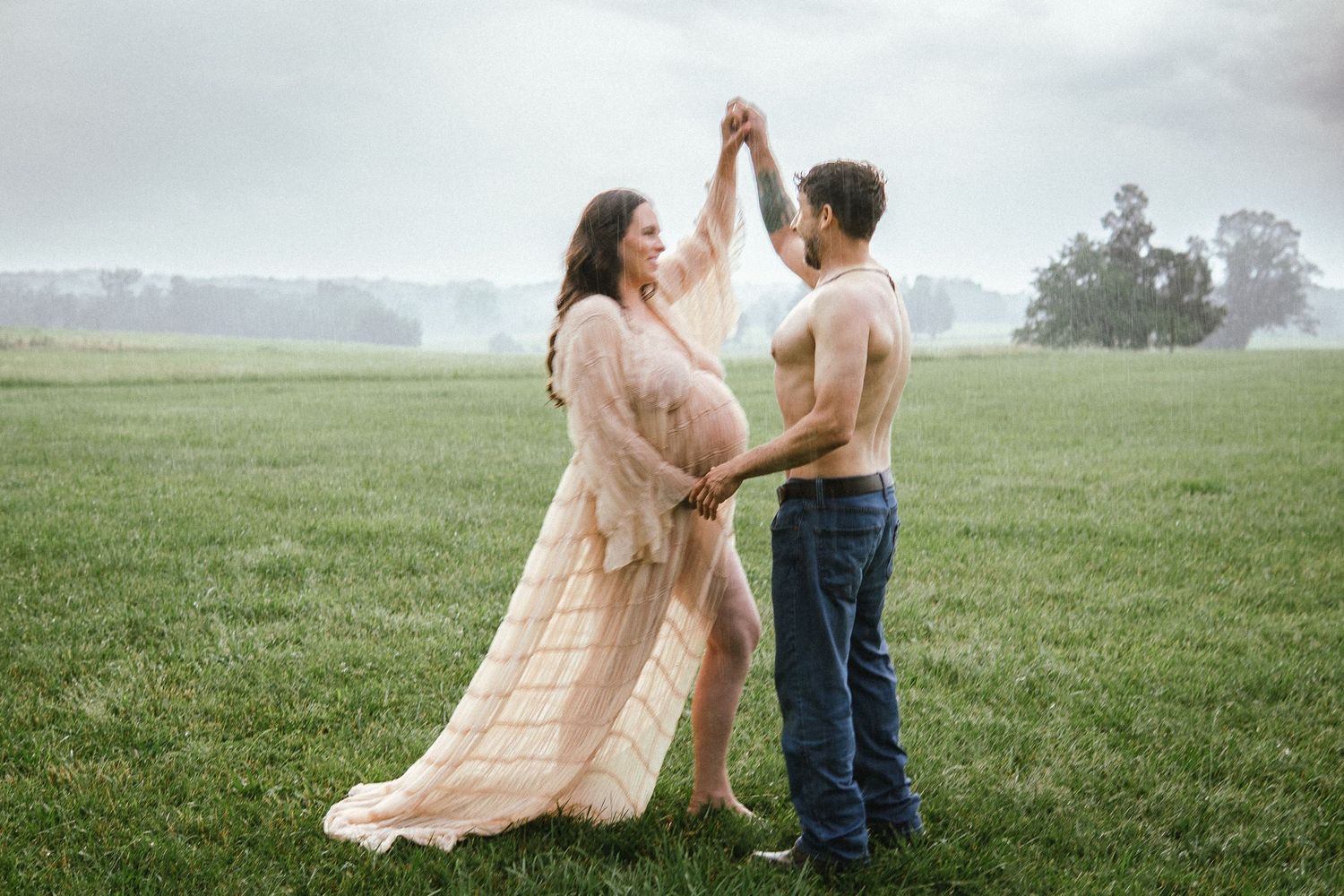 Two people dance together in an ethereal foggy field at dawn wearing blue denim and a flowing peach dress.