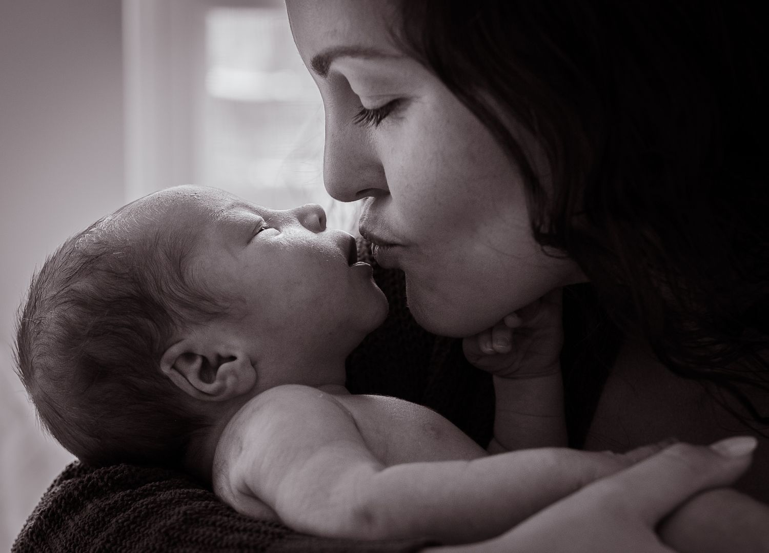 Intimate black and white portraits of tender family moments with newborn.