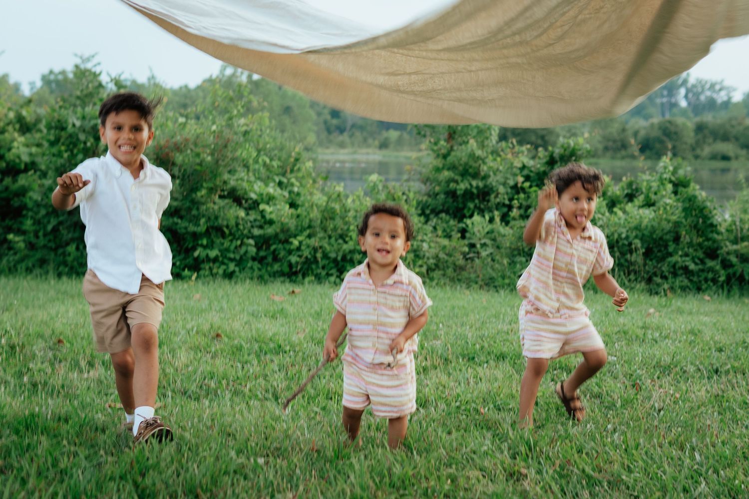 Three children running and playing under a canopy outdoors.