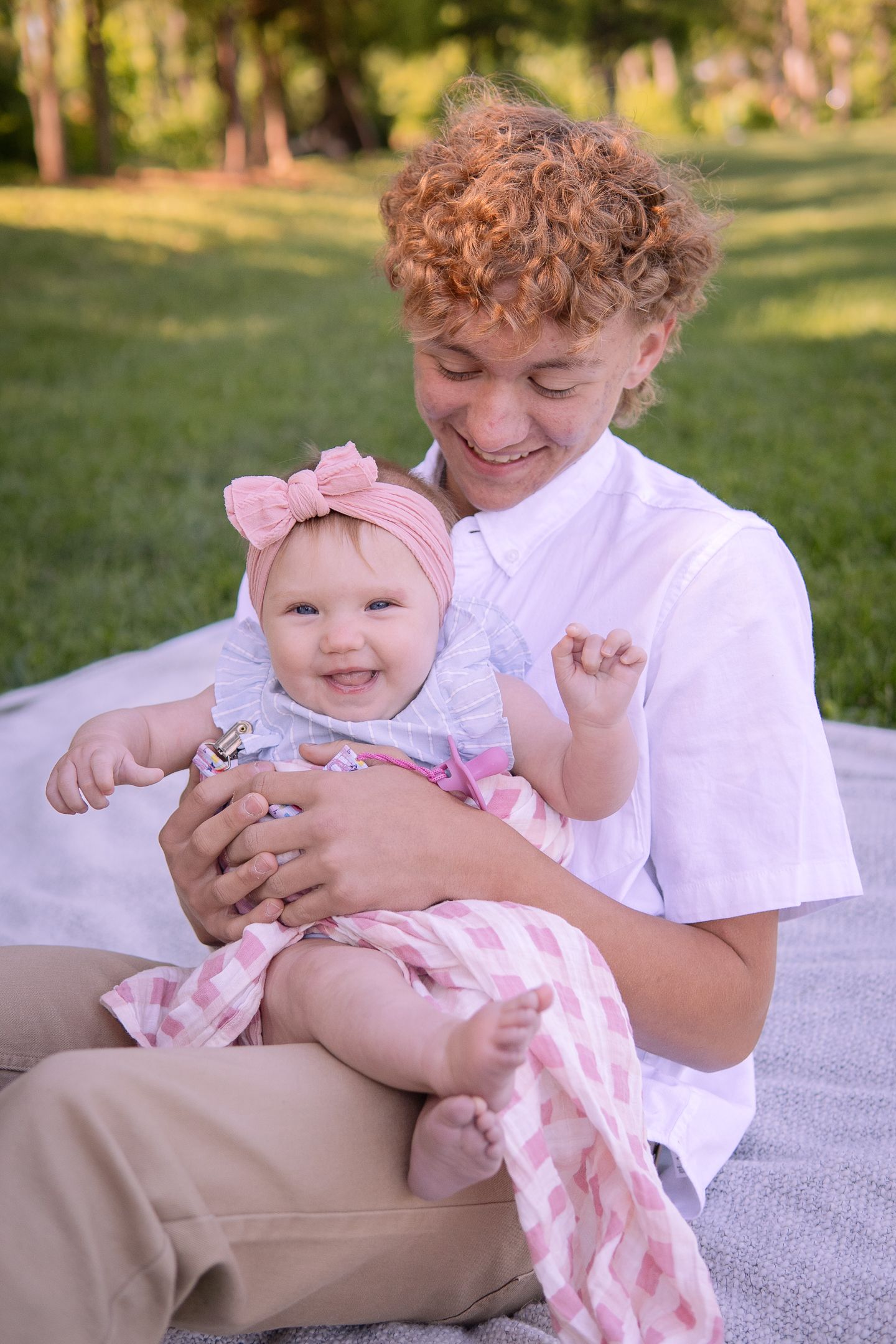 Sweet moment between two people on a picnic blanket outdoors with pink bow accessories.