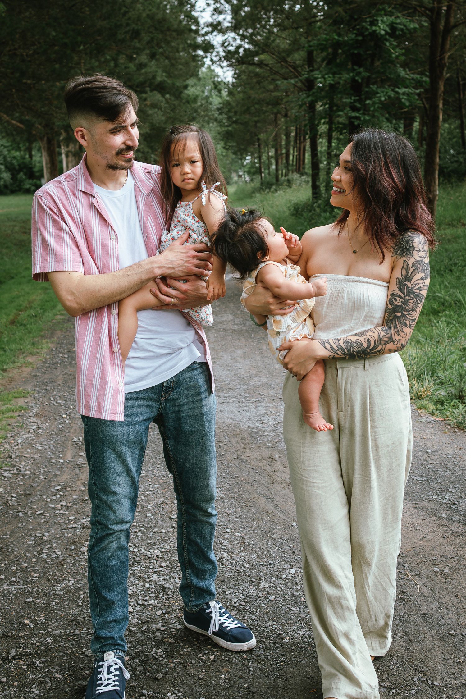 A family enjoying time together on a forest path wearing casual summer outfits.