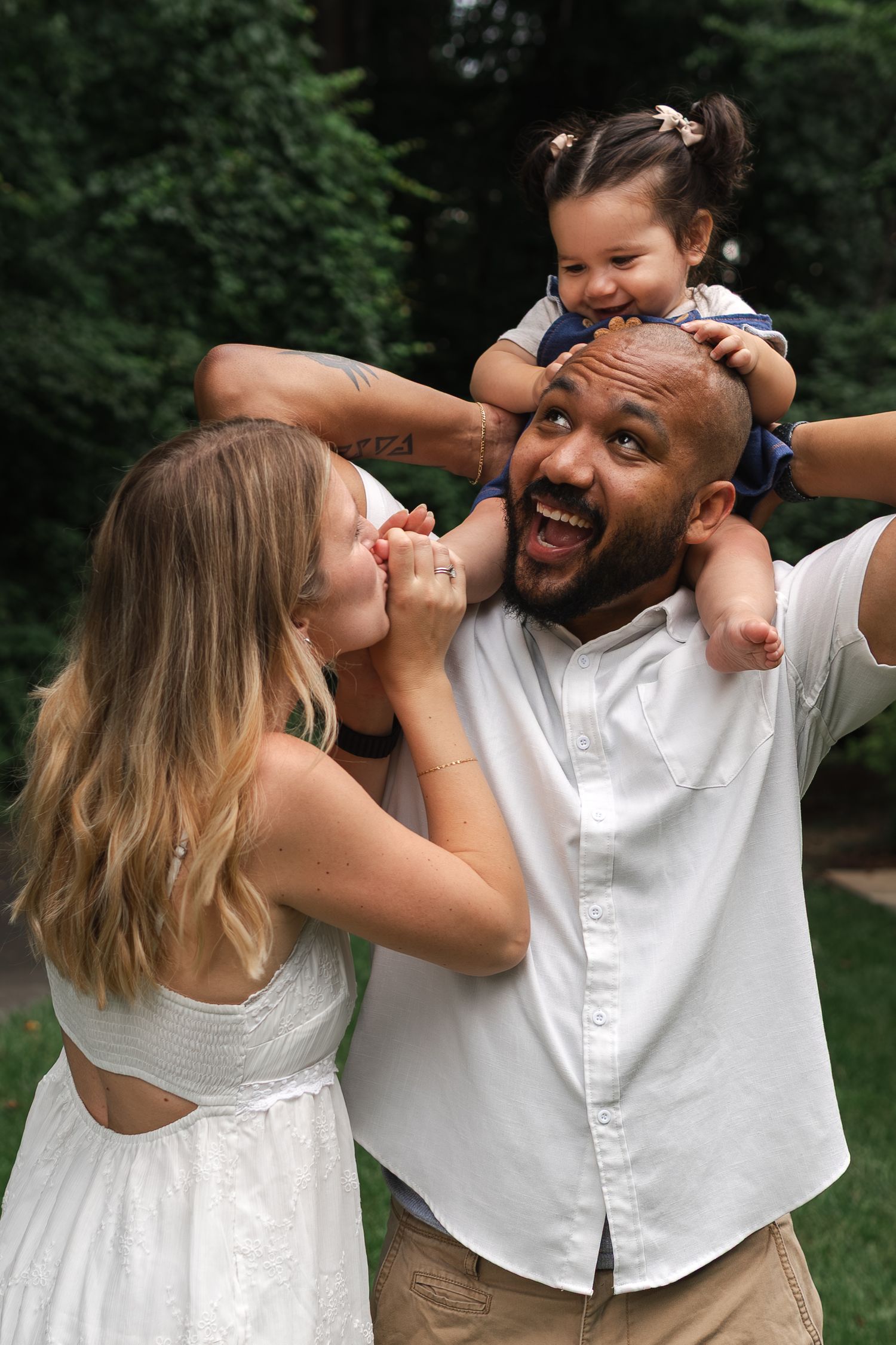 A joyful family laughs together outdoors while having fun in a garden setting.