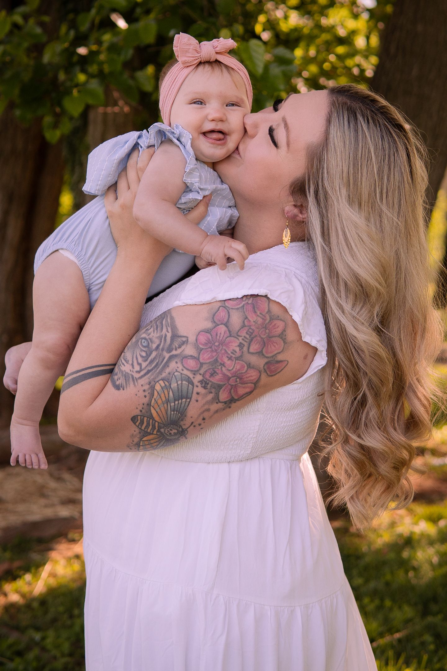 Sweet moment captured outdoors showing affection and laughter between two people in soft natural lighting.