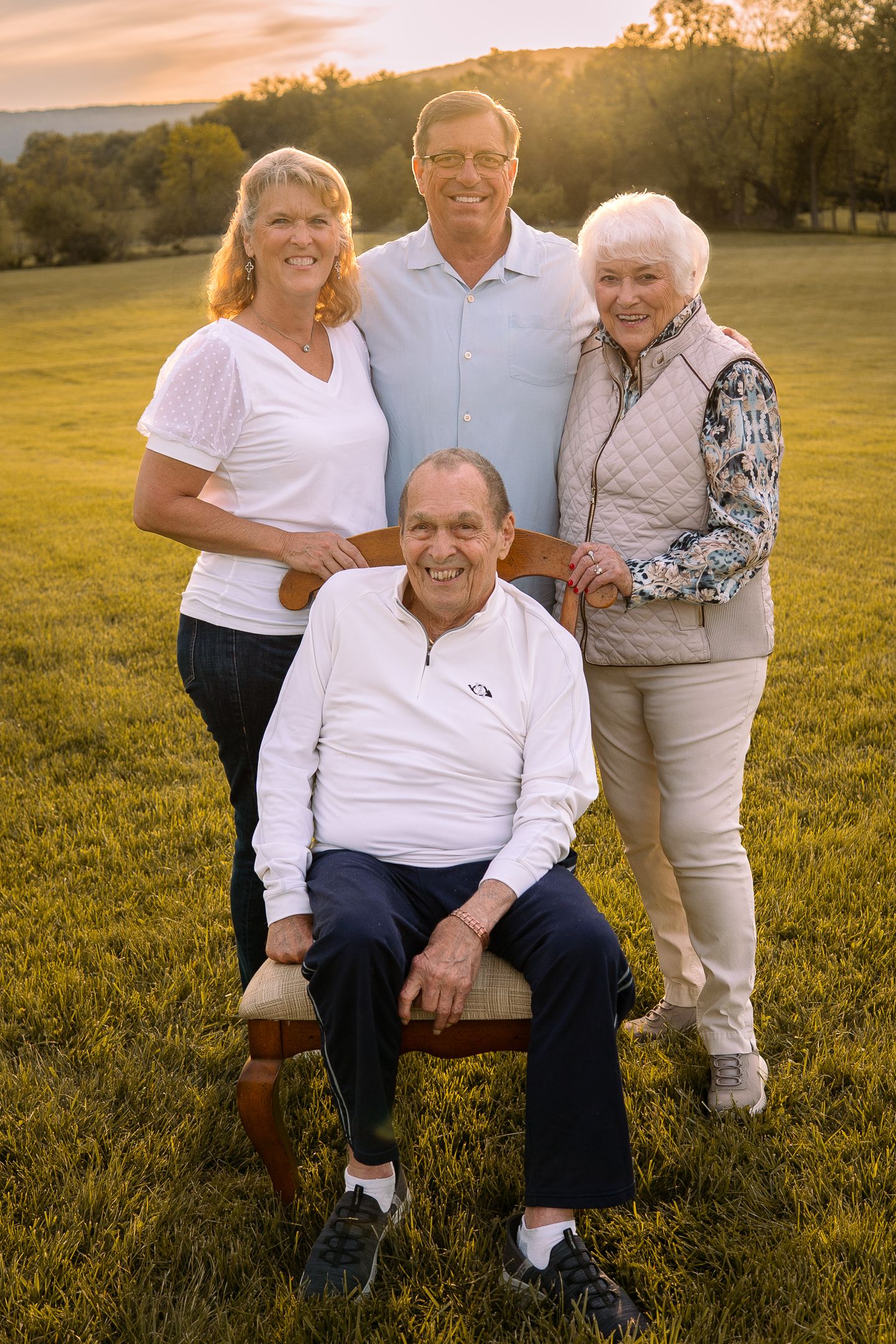 Family members pose together outdoors during sunset in a grassy field.