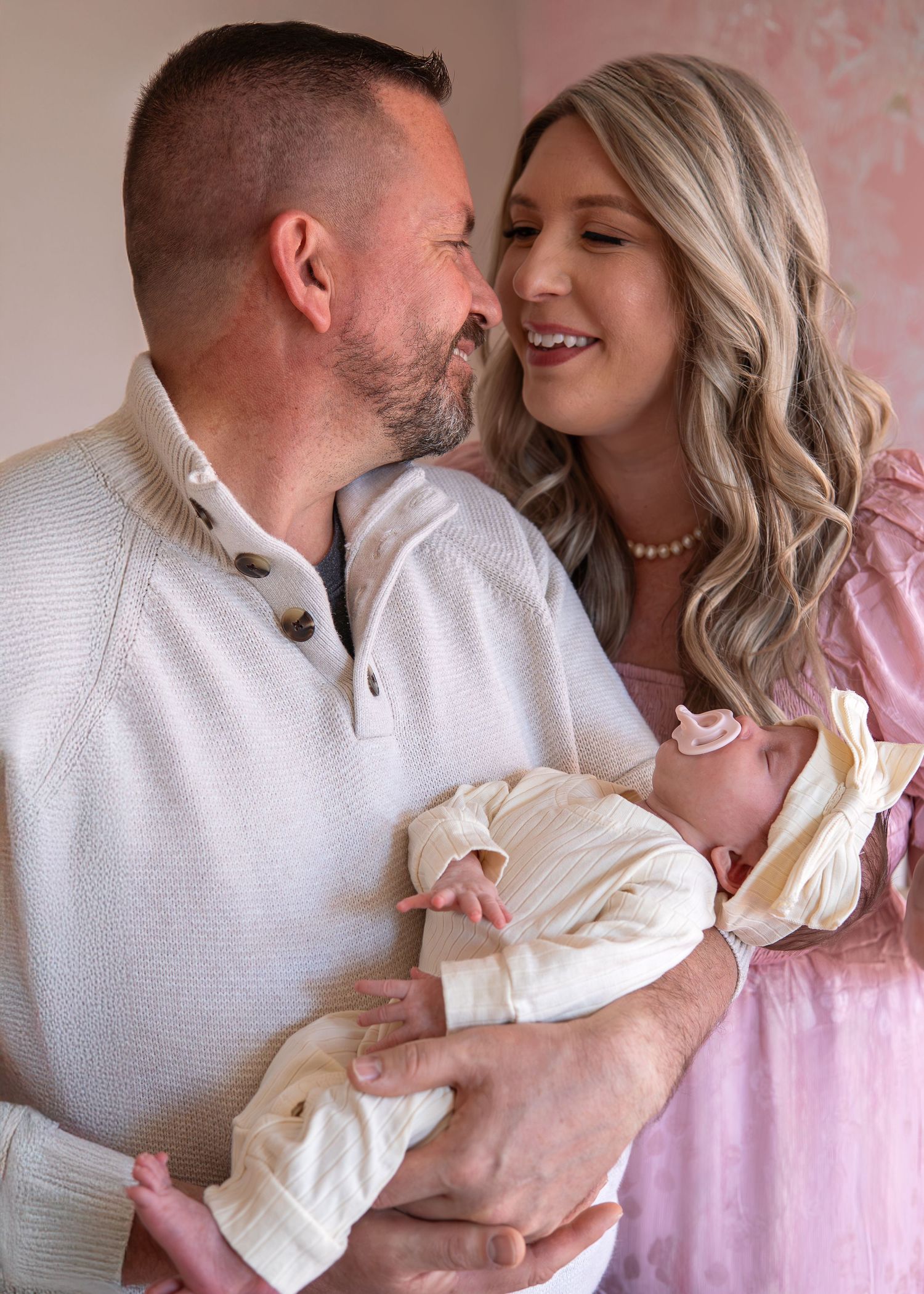 A couple shares tender moments in a series of intimate photos against a pink backdrop.