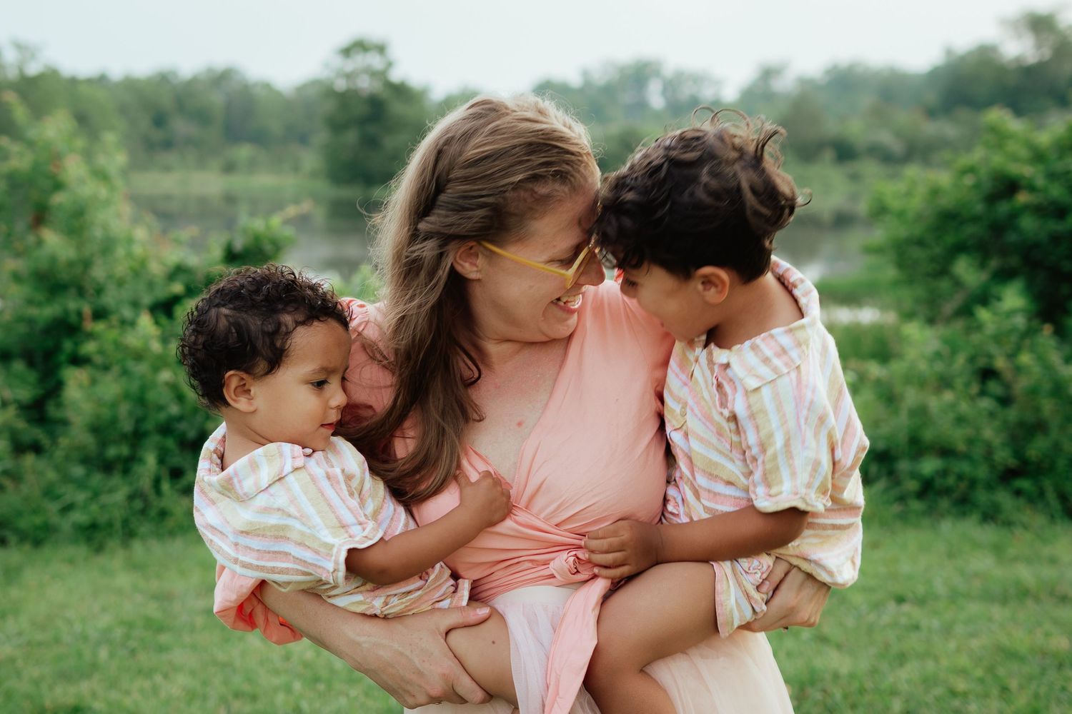 Tender moment between parent and two young children sitting together outdoors.