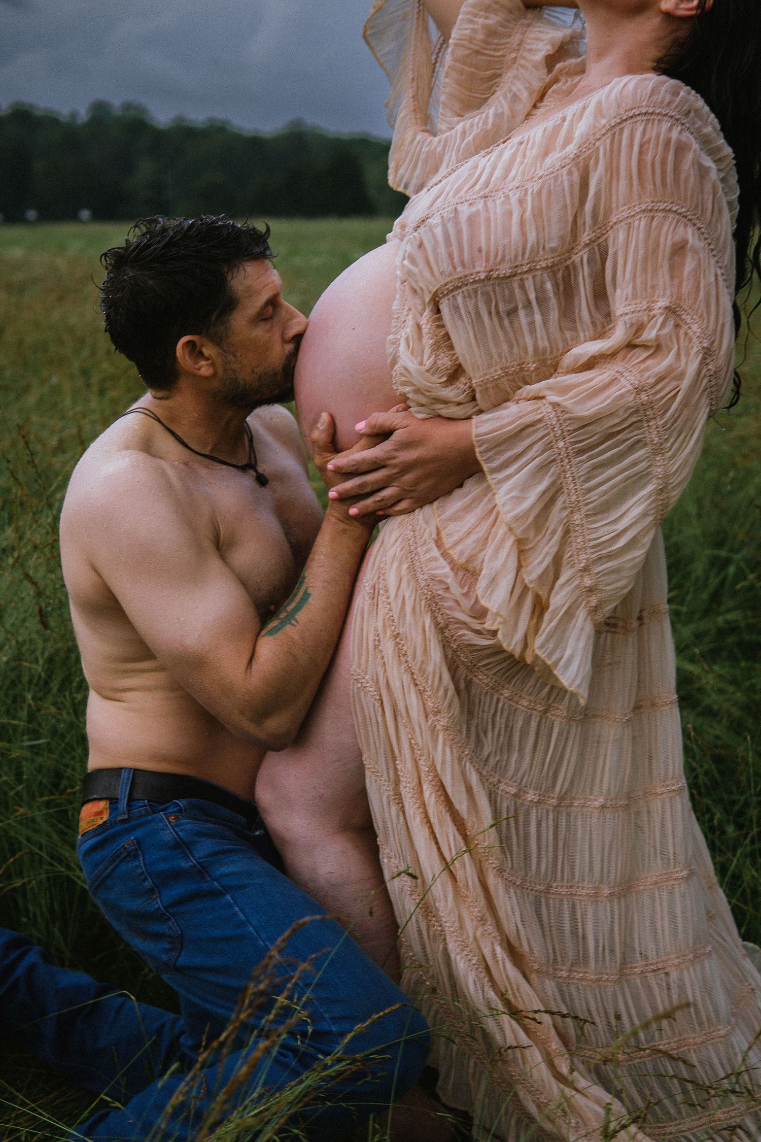 An intimate maternity photography session showing tender moments between expecting parents in a field.