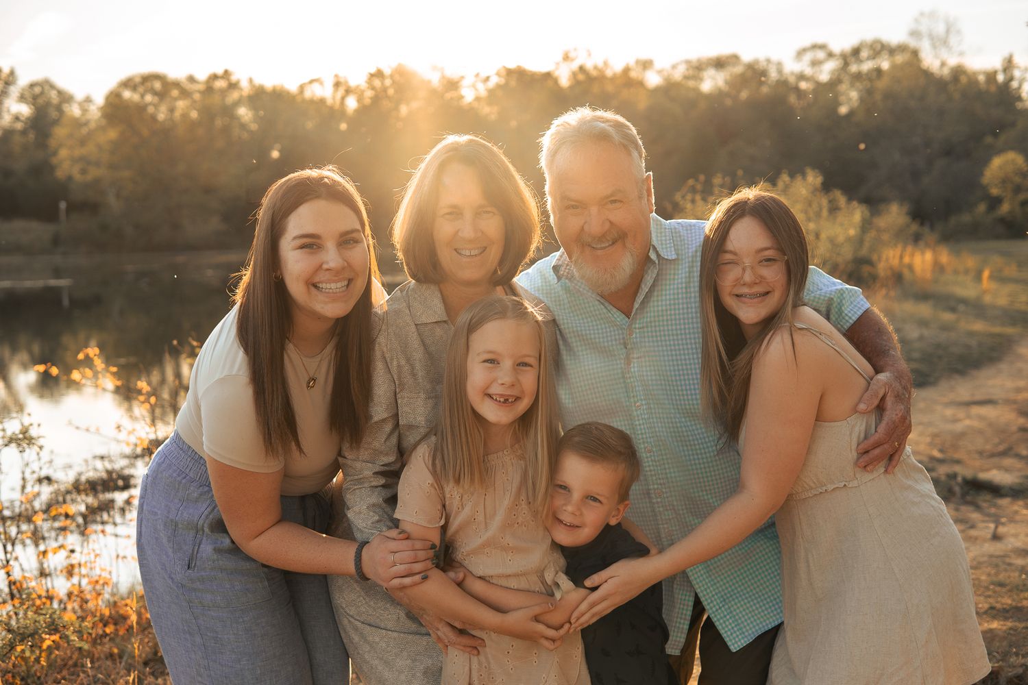 A family of six poses together warmly at sunset by a serene lake in Haymarket, Virginia.