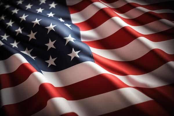 Close-up view of American flag waving with dramatic lighting showing red and white stripes and stars against dark background.