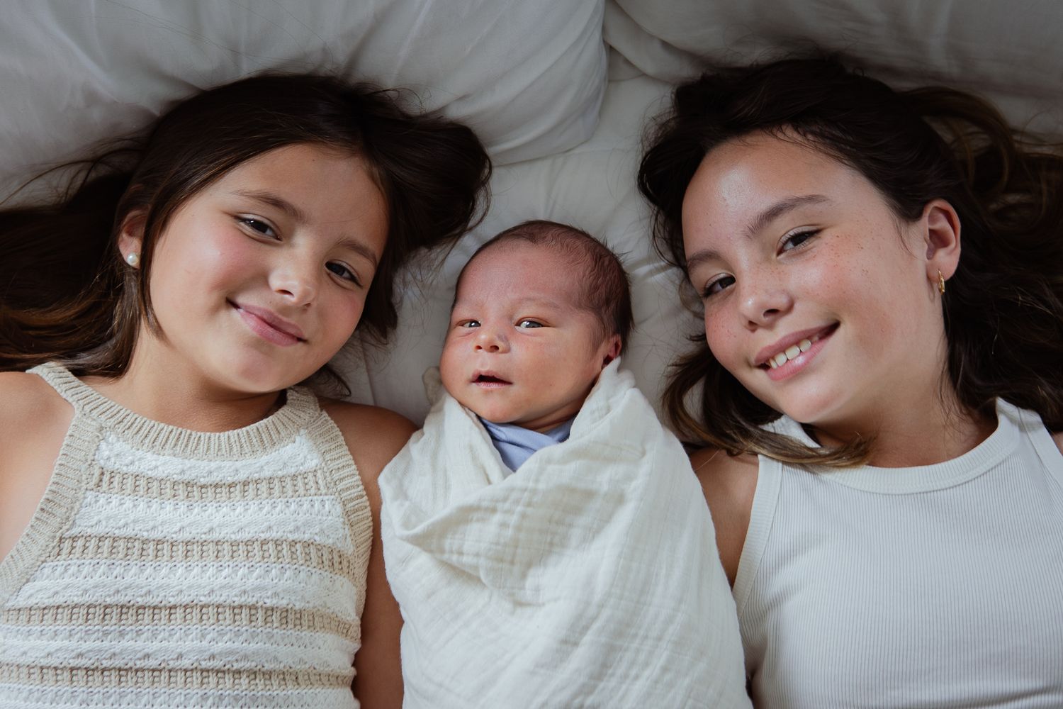 Family members in white tops share tender moments while laying together.