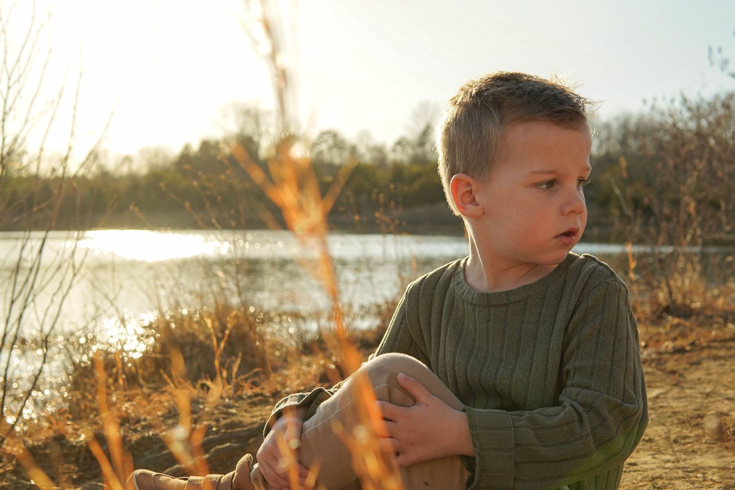 Young child explores outdoor natural setting at sunset while wearing a gray t-shirt.