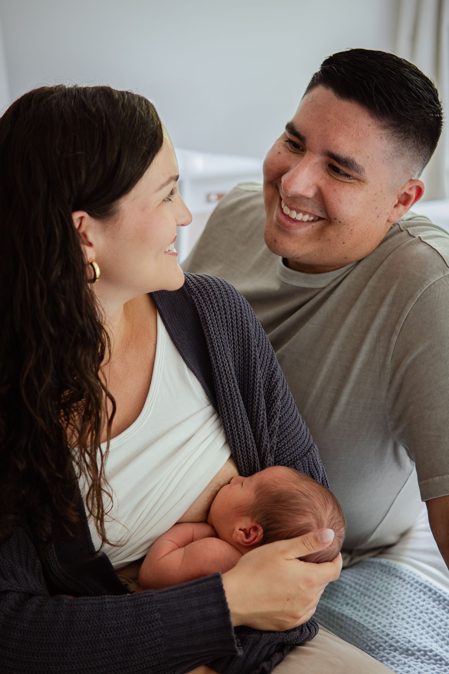 Intimate family moment with a newborn baby on a comfortable bed.