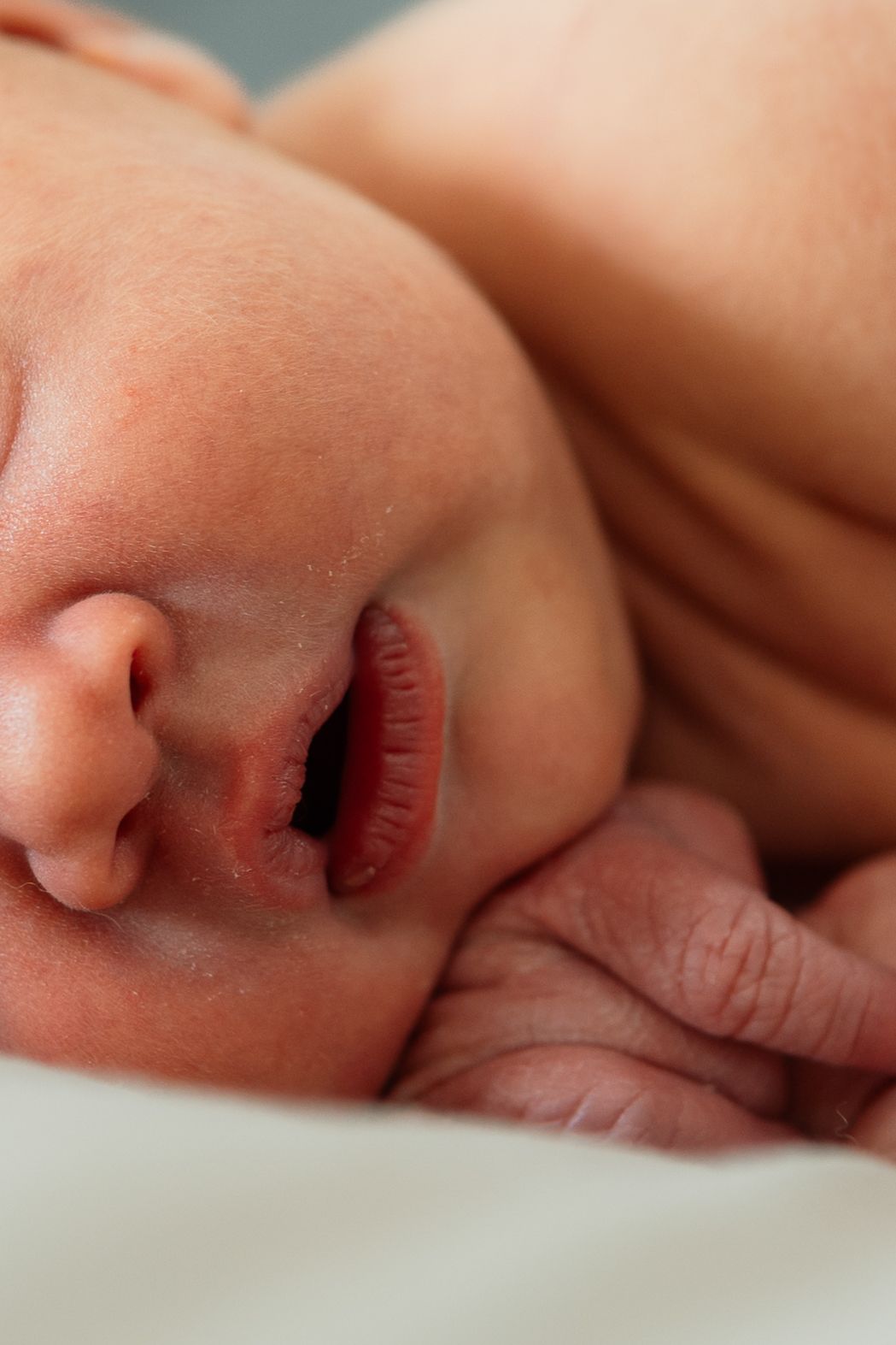 Peaceful close-up of sleeping newborn's face showing tiny nose and lips.
