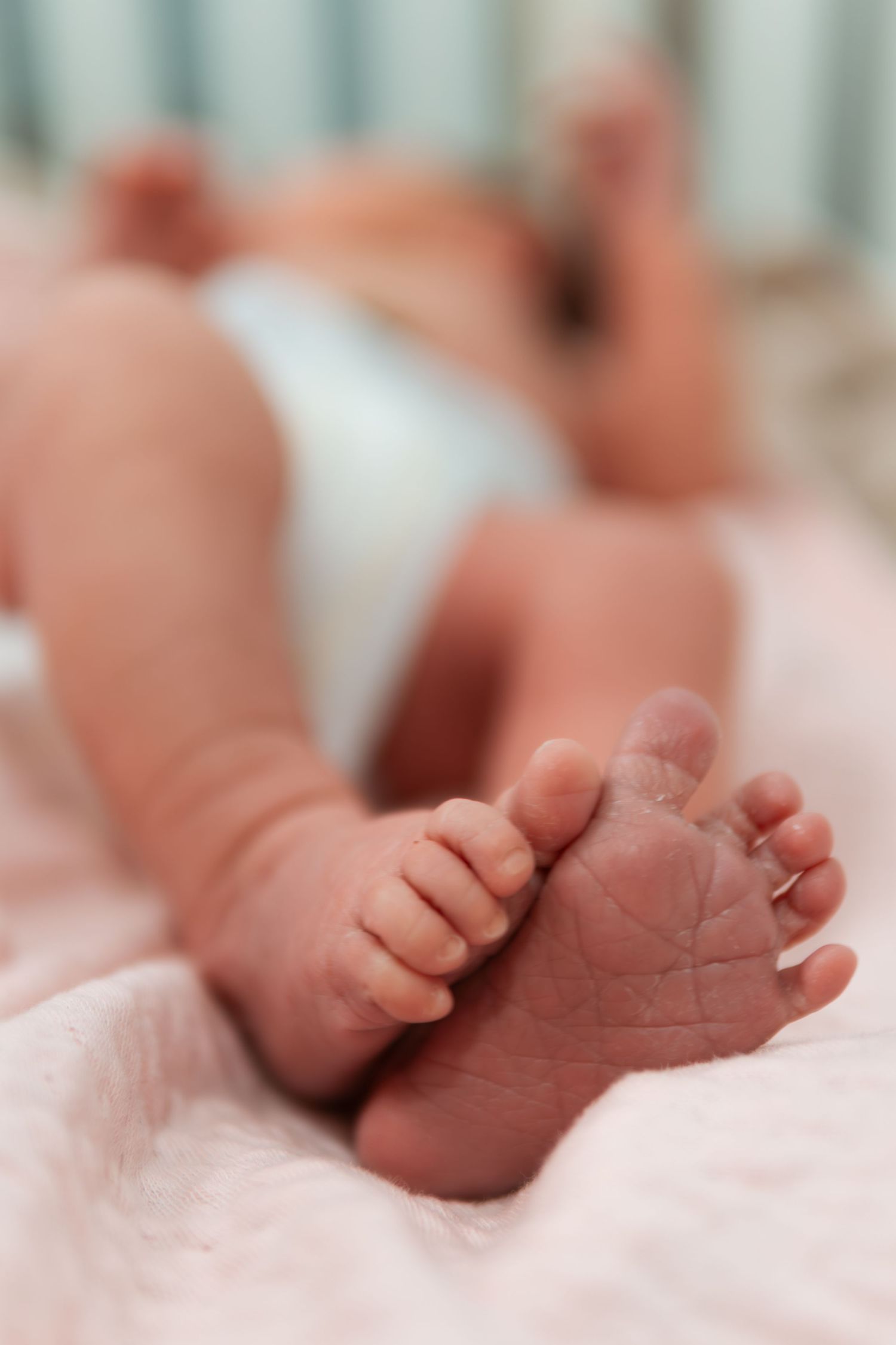 Close-up of tiny newborn baby feet resting on pink blanket.