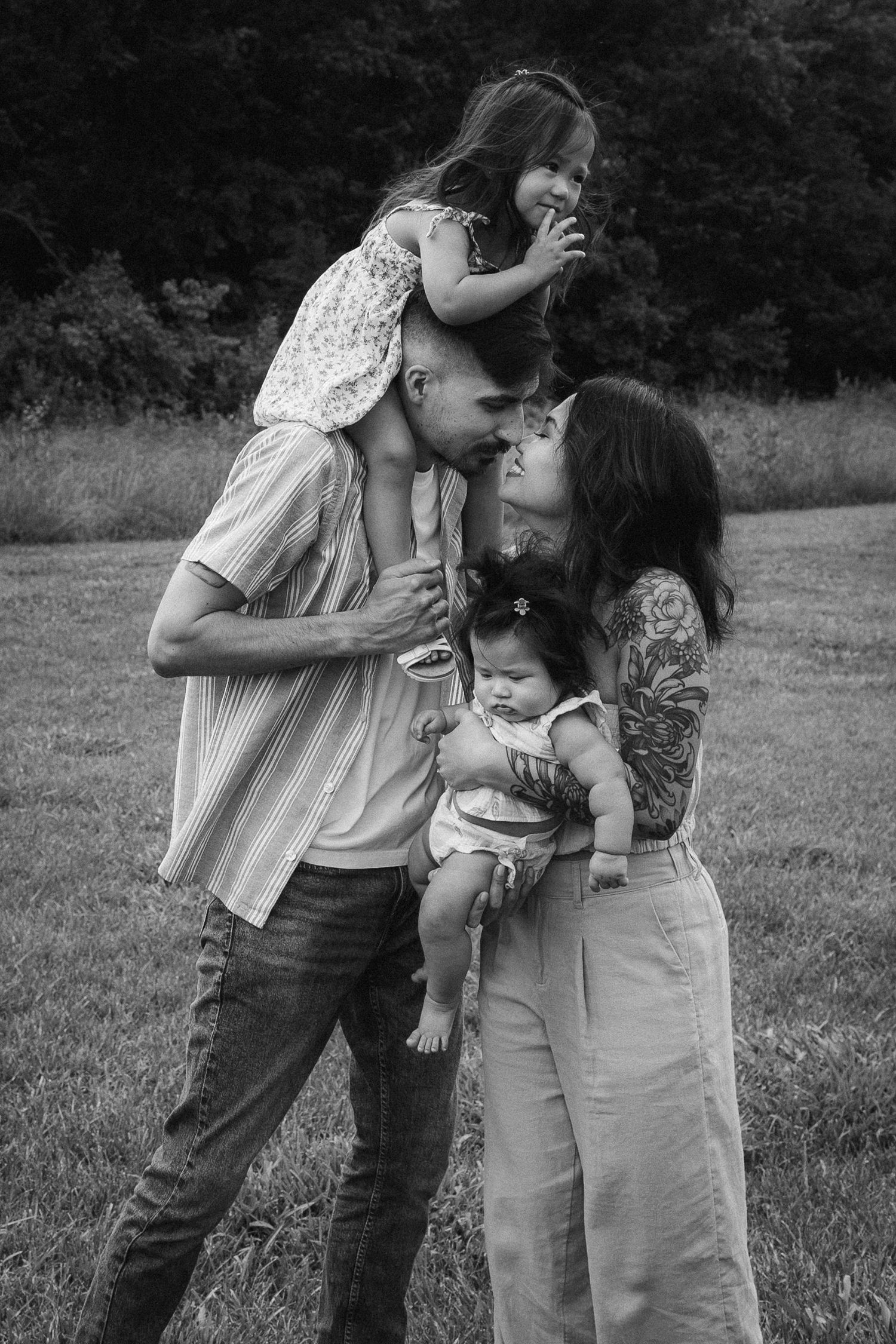 Family sharing tender moments and embraces together in a park setting.