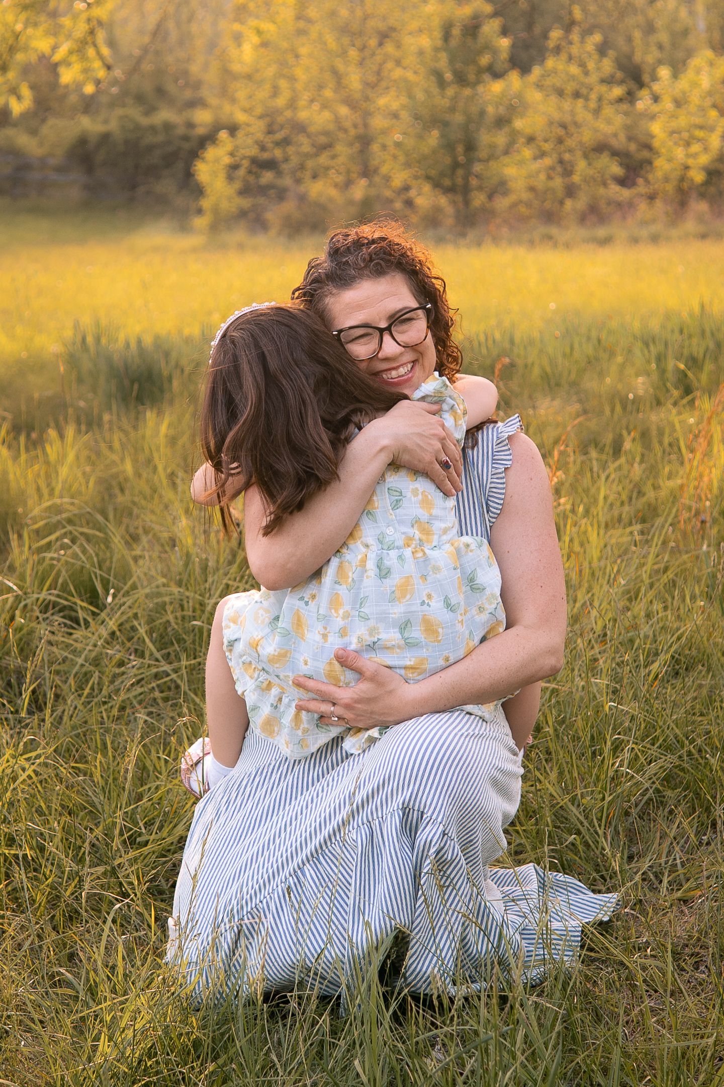 A tender embrace shared between two people in a sunlit meadow with golden autumn foliage in the background.