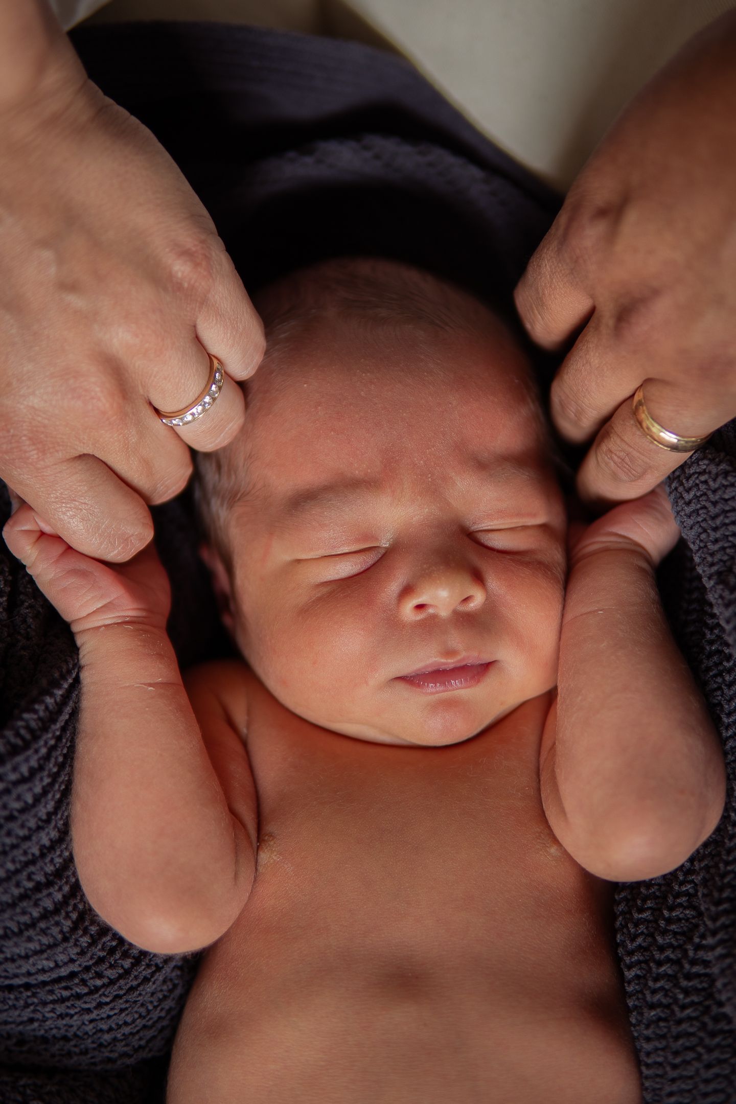 Close-up shots of a newborn baby's delicate features being gently touched by hands.