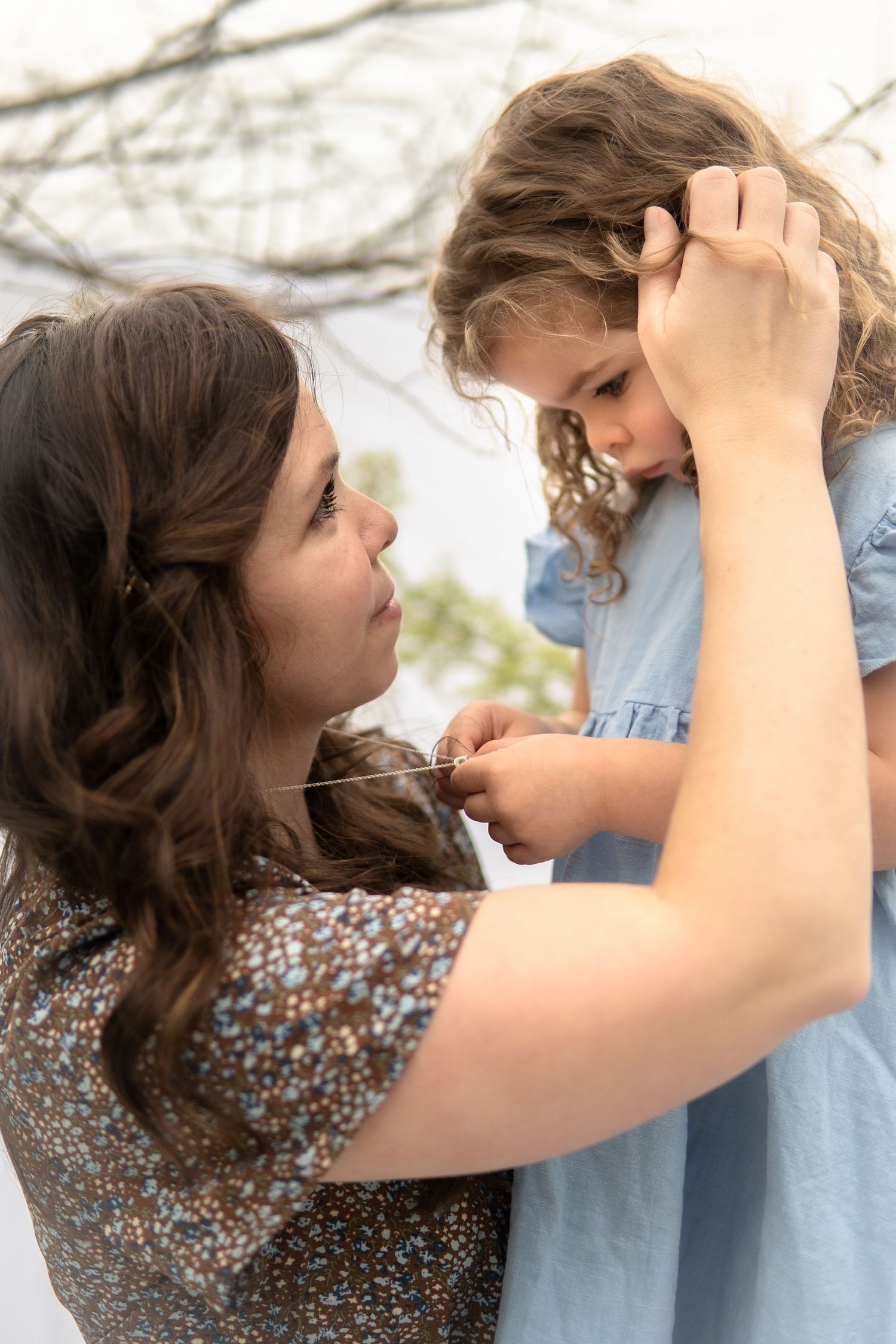 A tender moment between parent and child sharing an embrace outdoors on a bright sunny day.