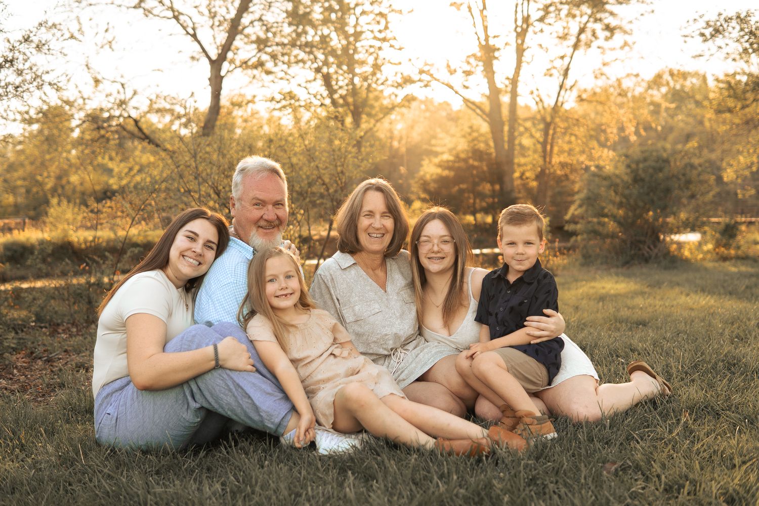 A group sits together on grass during golden hour in a natural outdoor setting at sunset in Haymarket, Virginia.
