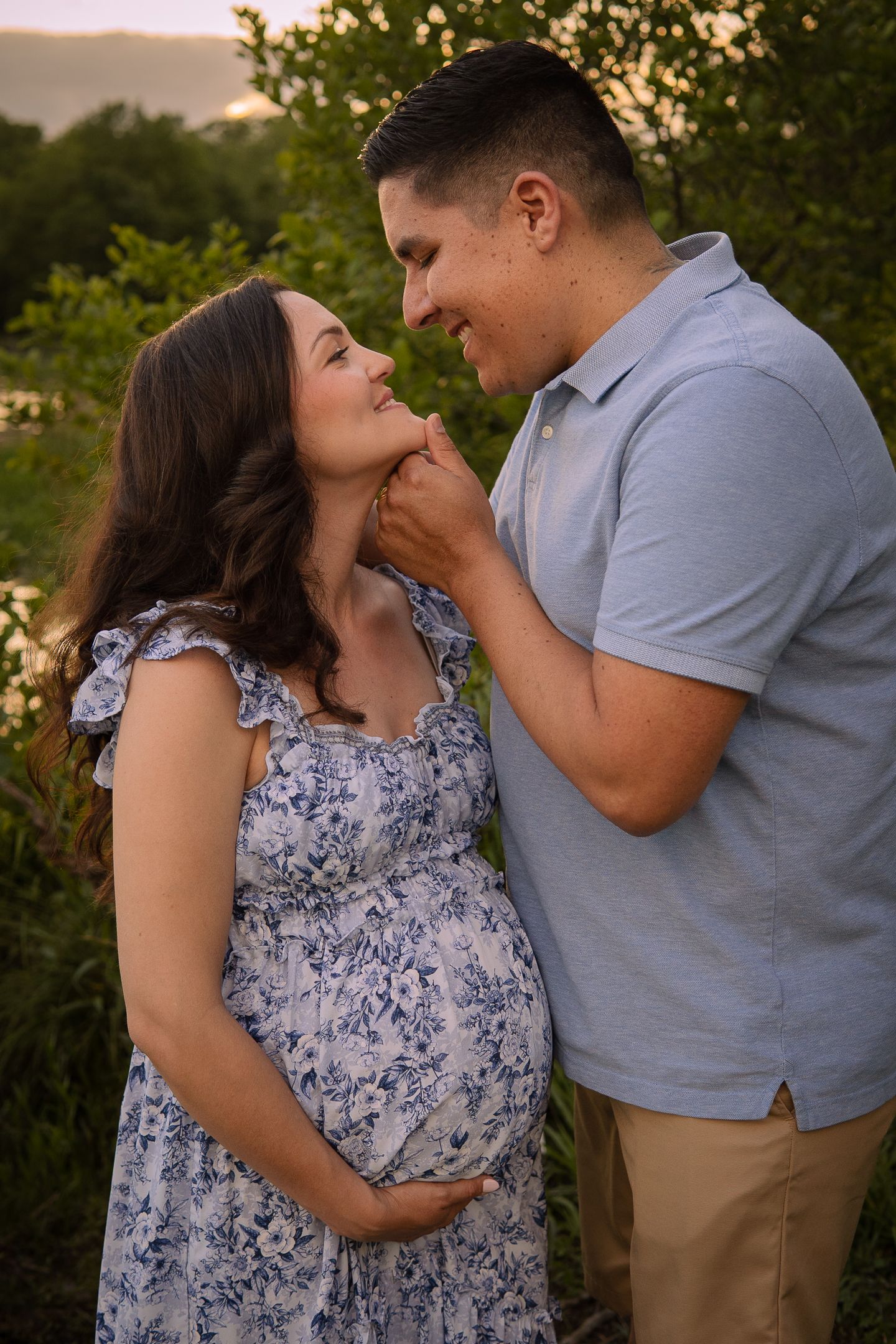 An intimate maternity portrait of a couple embracing by the lake during golden hour.