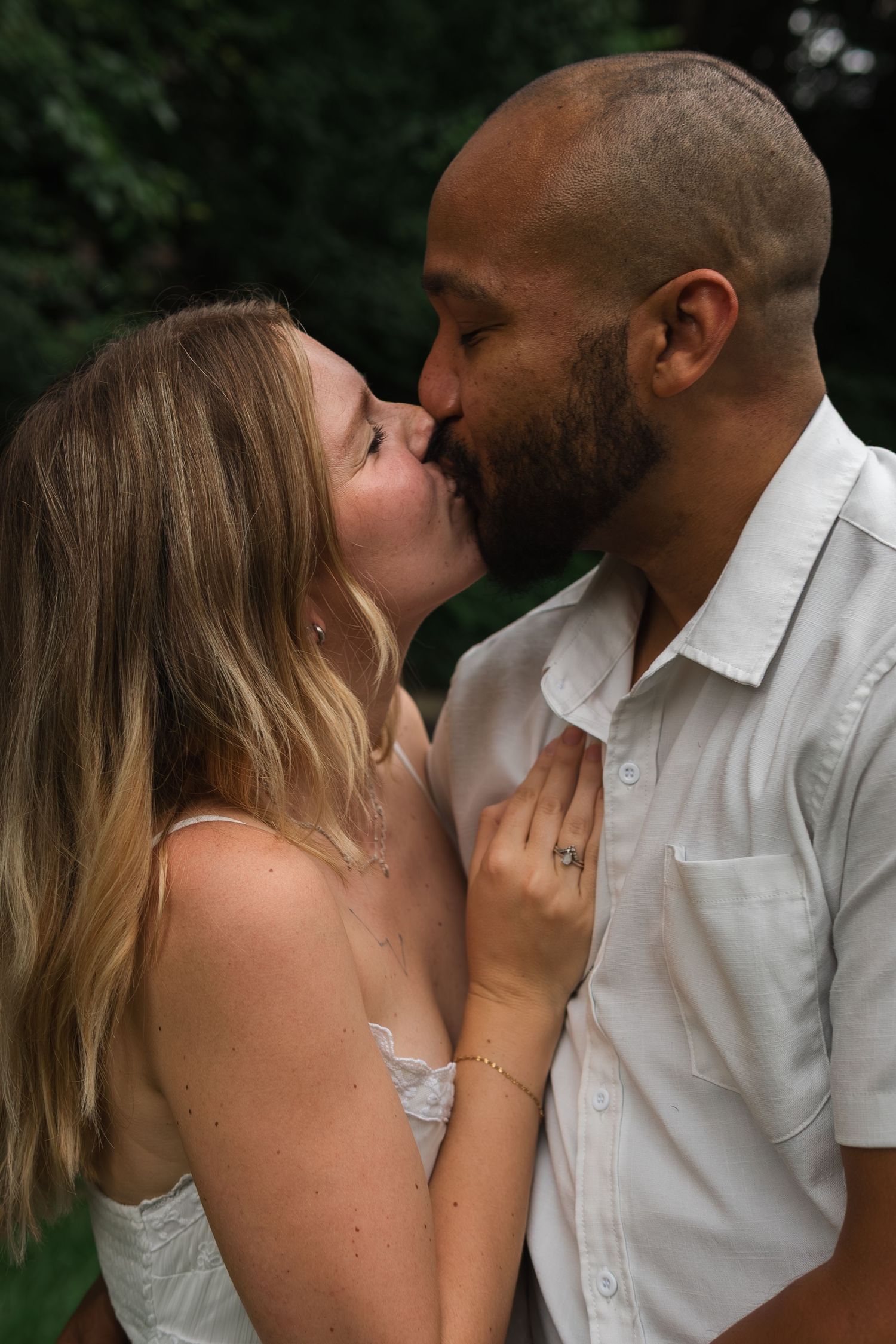 A tender moment between a couple sharing a kiss in an outdoor setting.