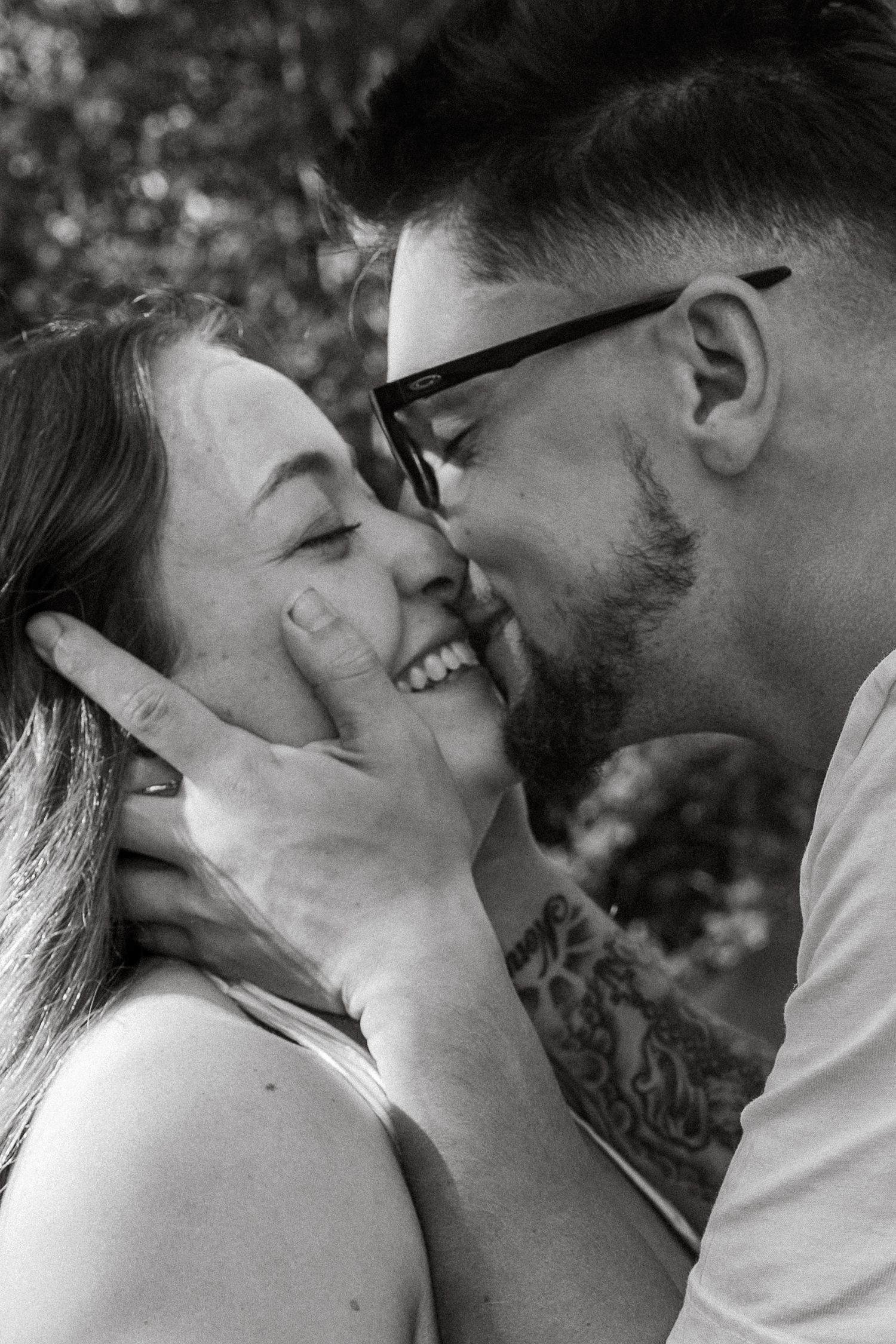 A romantic black and white photo series showing tender kisses and intimate moments between a couple outdoors.