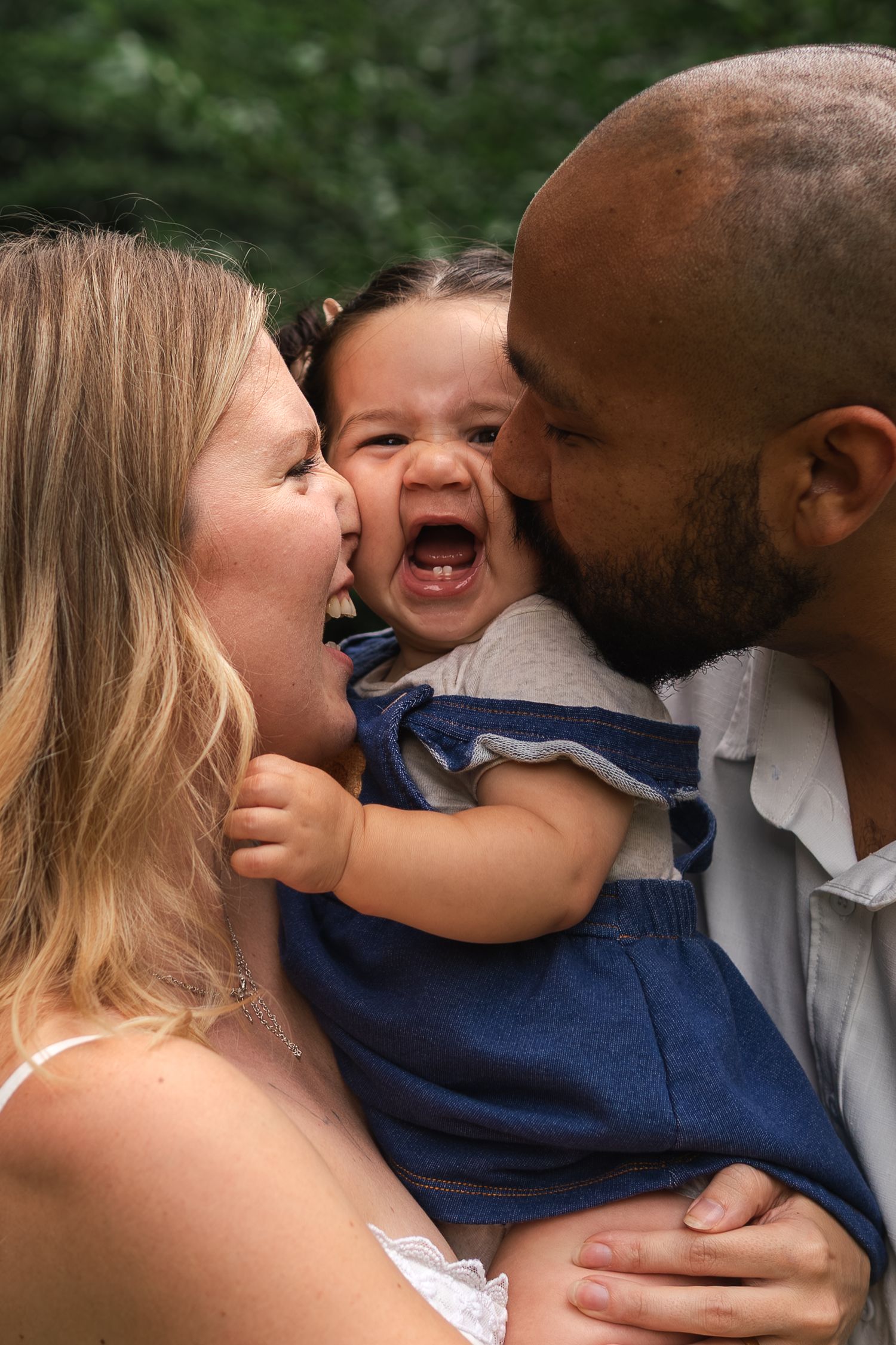 A happy family shares a playful moment together as they snuggle close and laugh during an outdoor photo.
