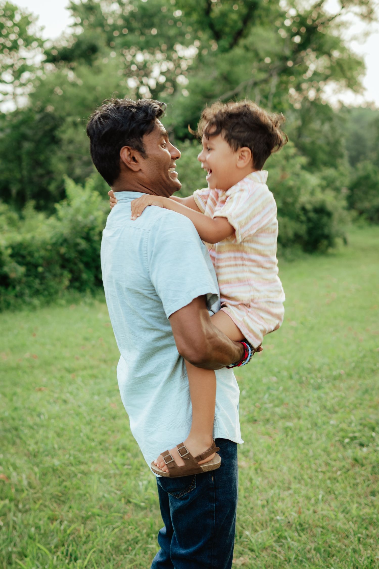 Candid moment of parent and child sharing a laugh together in a park setting.