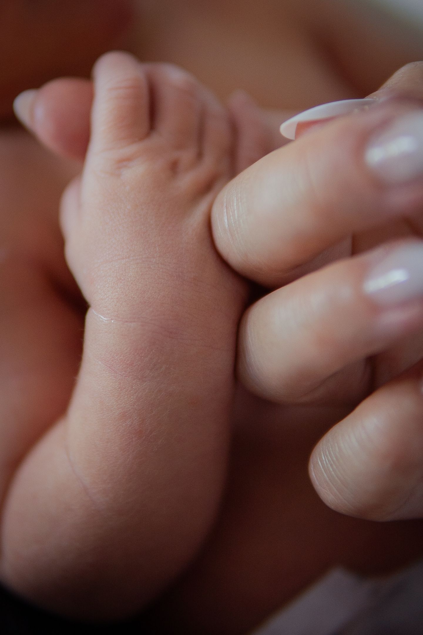 Close-up image of tiny newborn baby fingers being held gently.