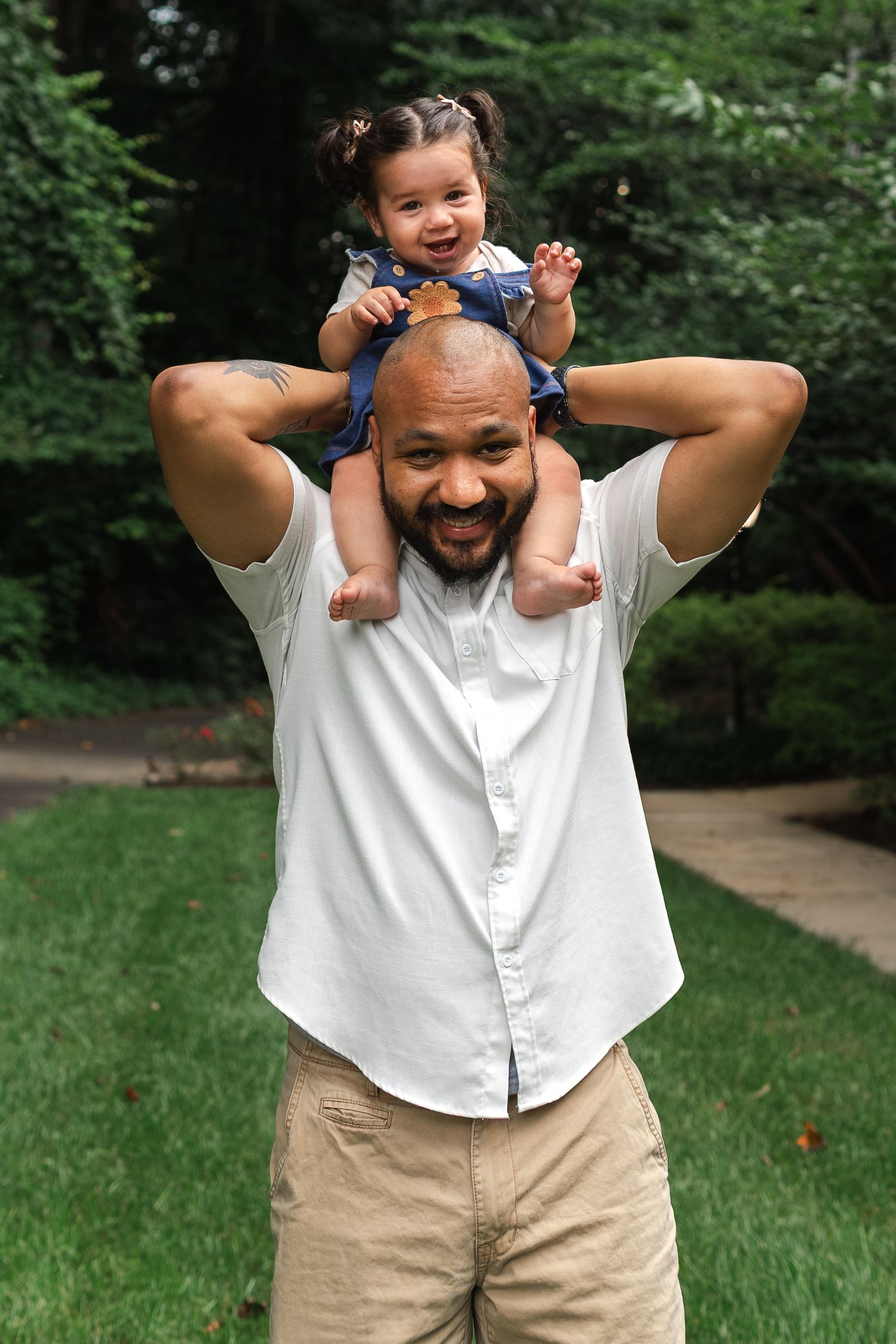 A smiling adult and young child playing together outdoors in a park setting, showing joyful expressions and gestures.