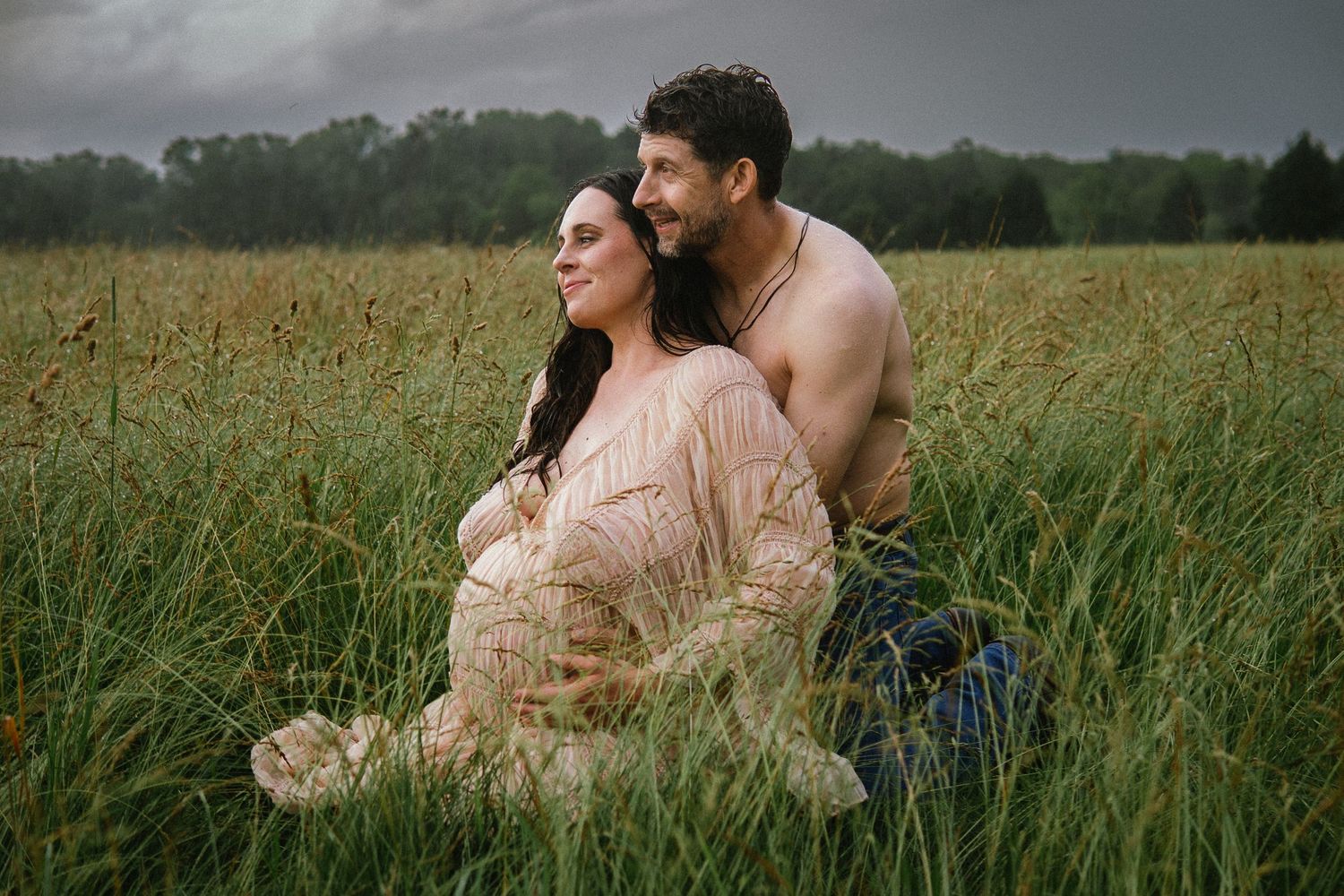 Romantic couple sitting together lovingly in a serene green wheat field at sunset.