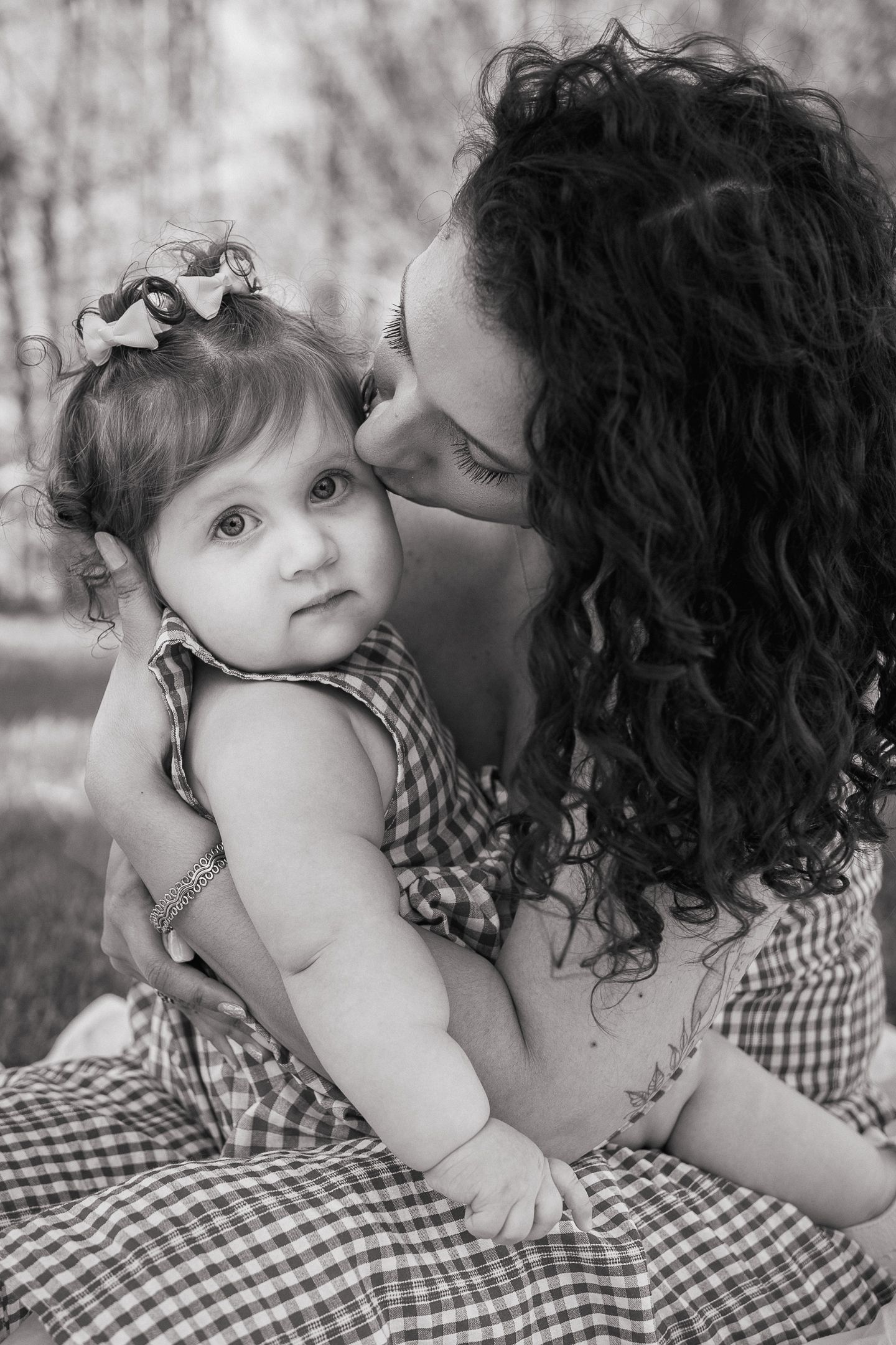 Mother gently kissing her baby’s cheek during an outdoor family photography session in Northern Virginia, captured by a lifestyle newborn ph