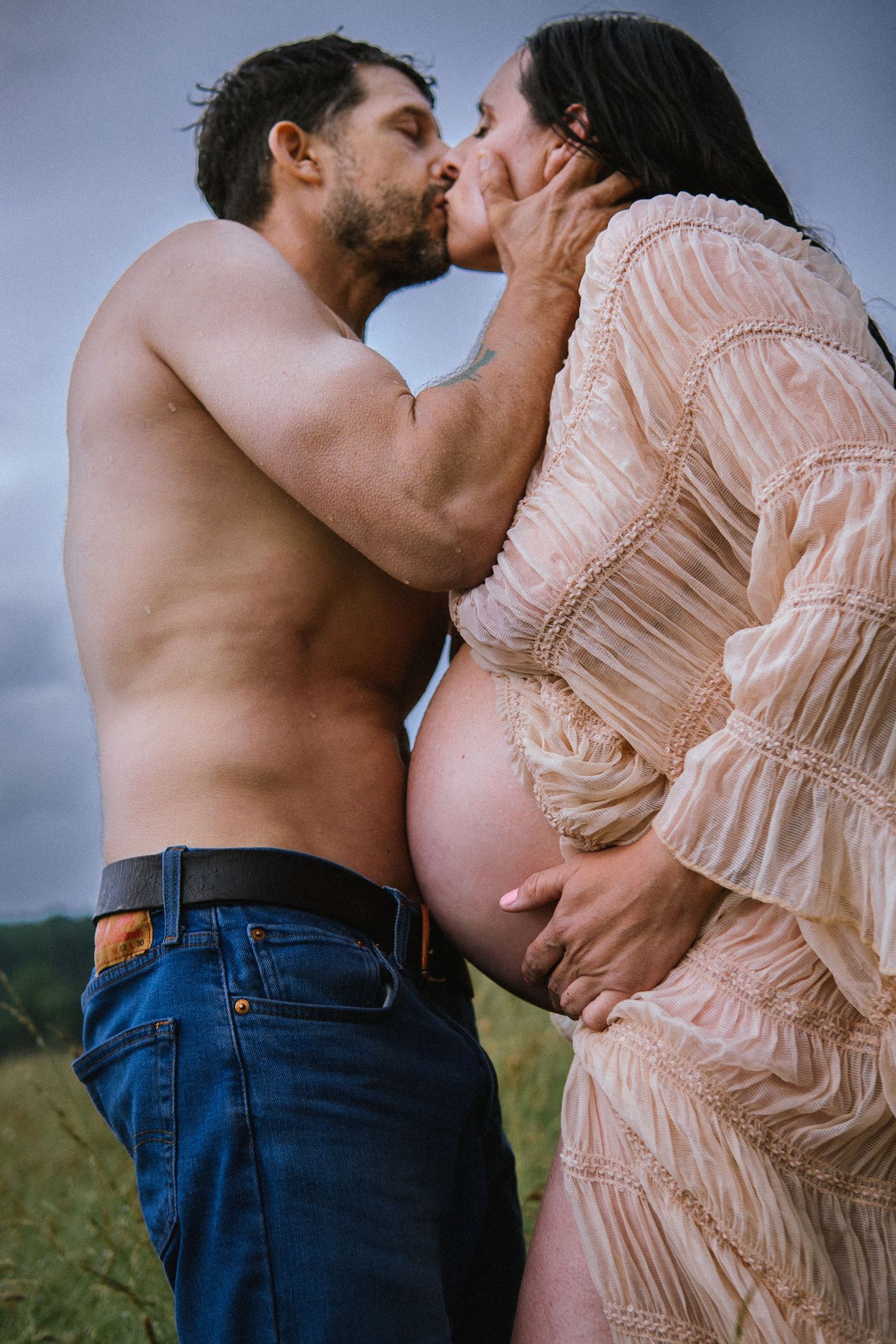 Intimate close-up of expectant couple sharing tender moment in outdoor setting.