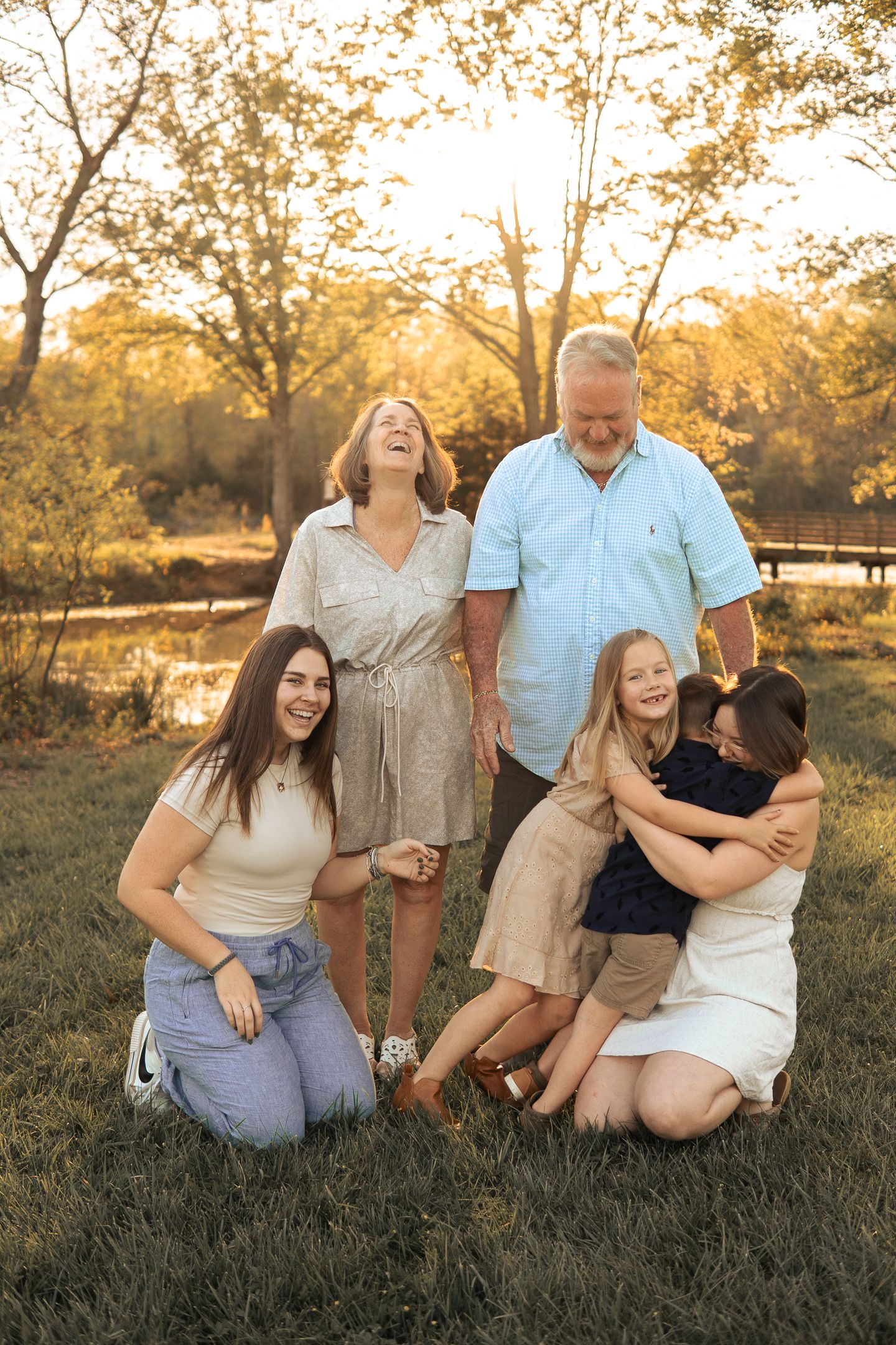 A group relaxes together outdoors during golden hour in a natural setting with autumn trees in the background in Haymarket, Virginia.
