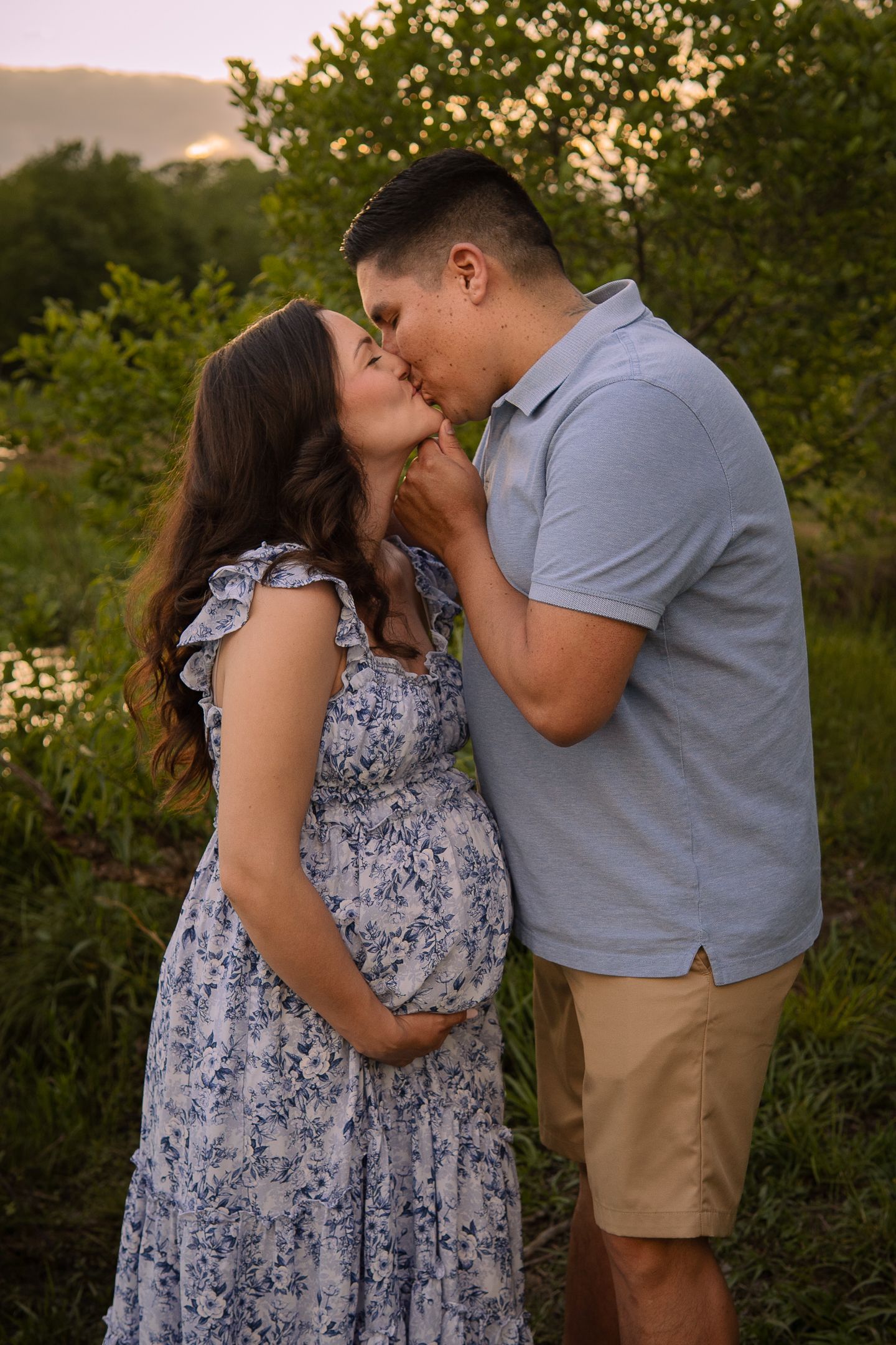 An intimate moment between expecting couple in a natural setting during golden hour.