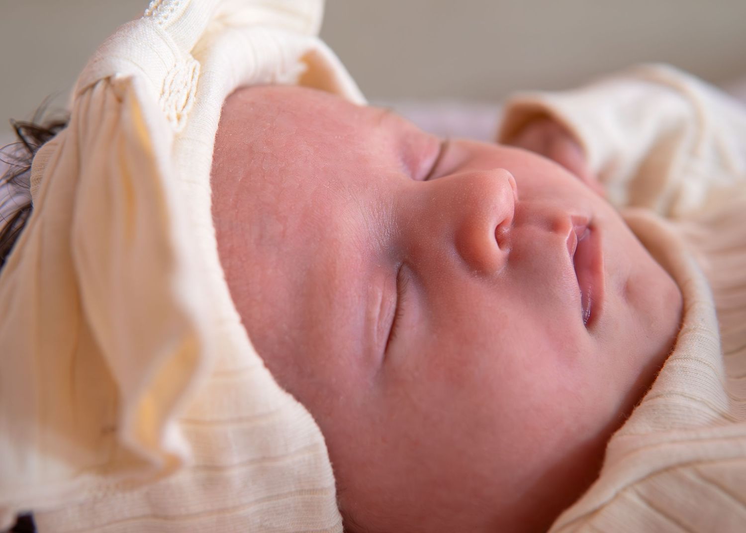 A sleeping baby swaddled in white blankets rests peacefully in a series of connected photos.
